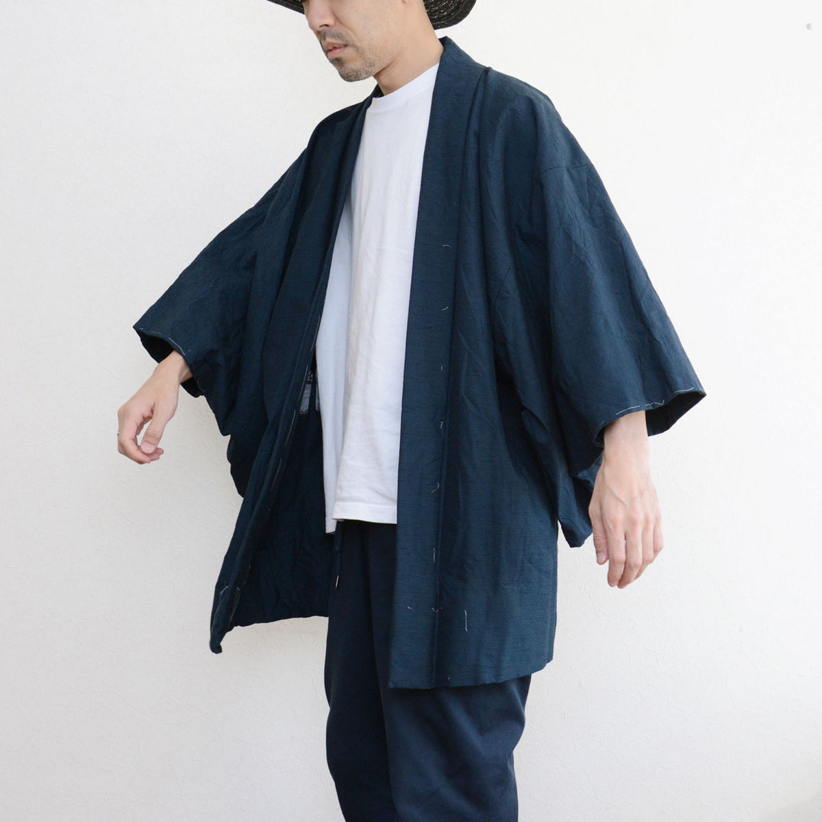Japanese vintage men's haori in deep blue-green with loose sleeves, worn over a white T-shirt and dark trousers.