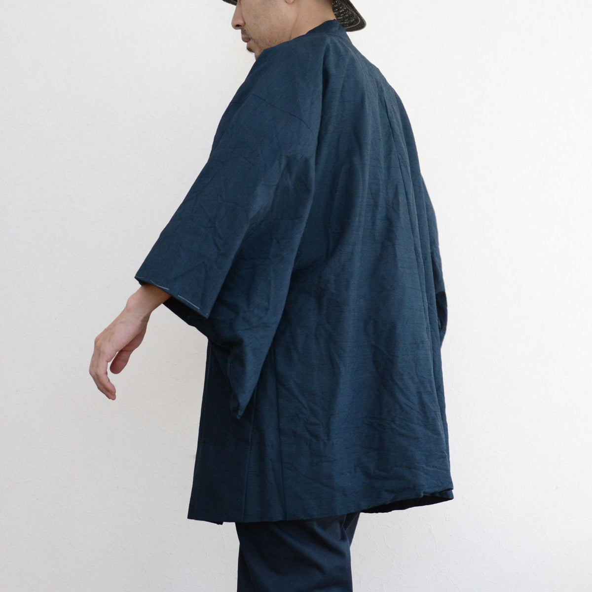 Deep blue-green Japanese vintage haori with a center seam and loose sleeves, worn with dark trousers.