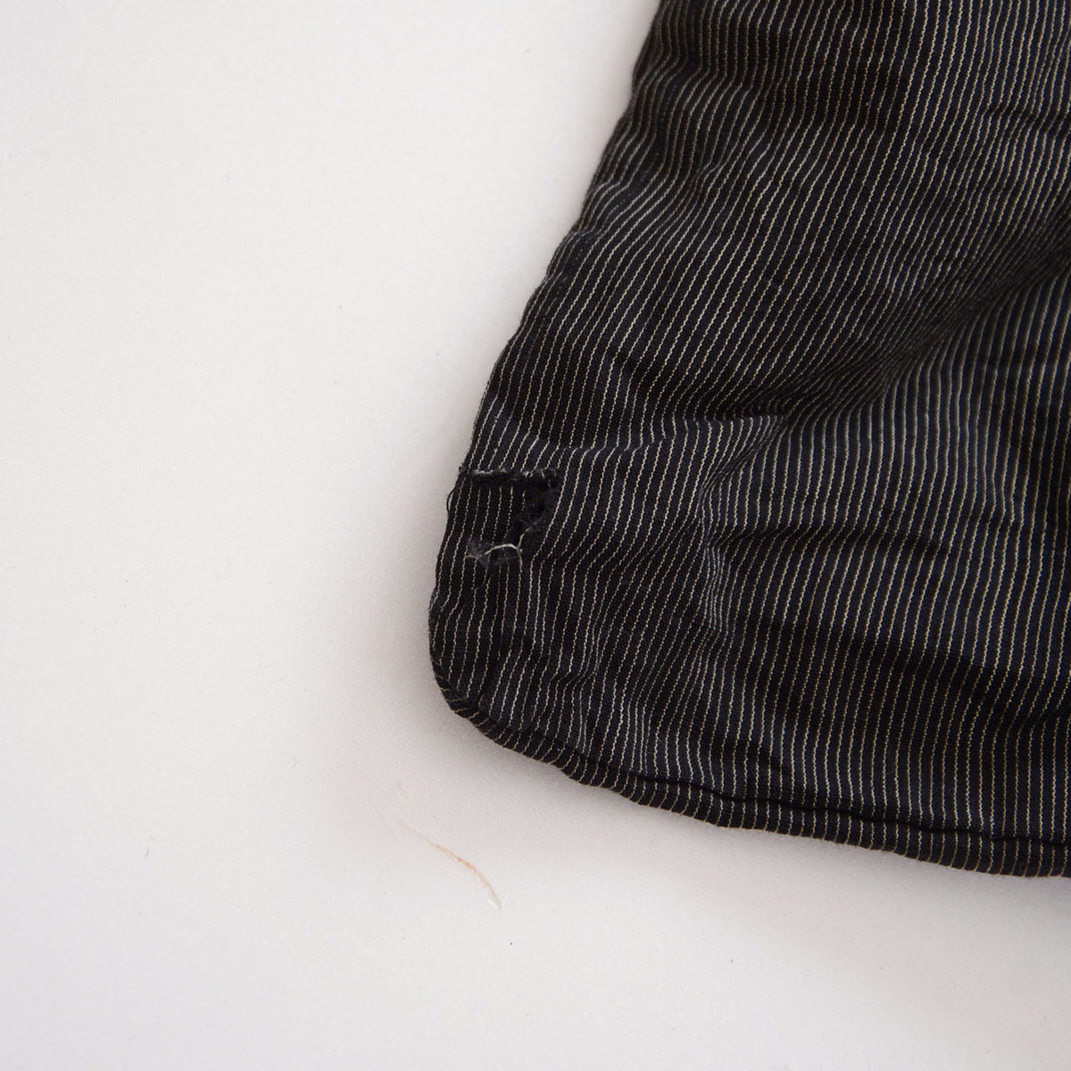 Tear and frayed threads in the fine-striped fabric of a vintage haori