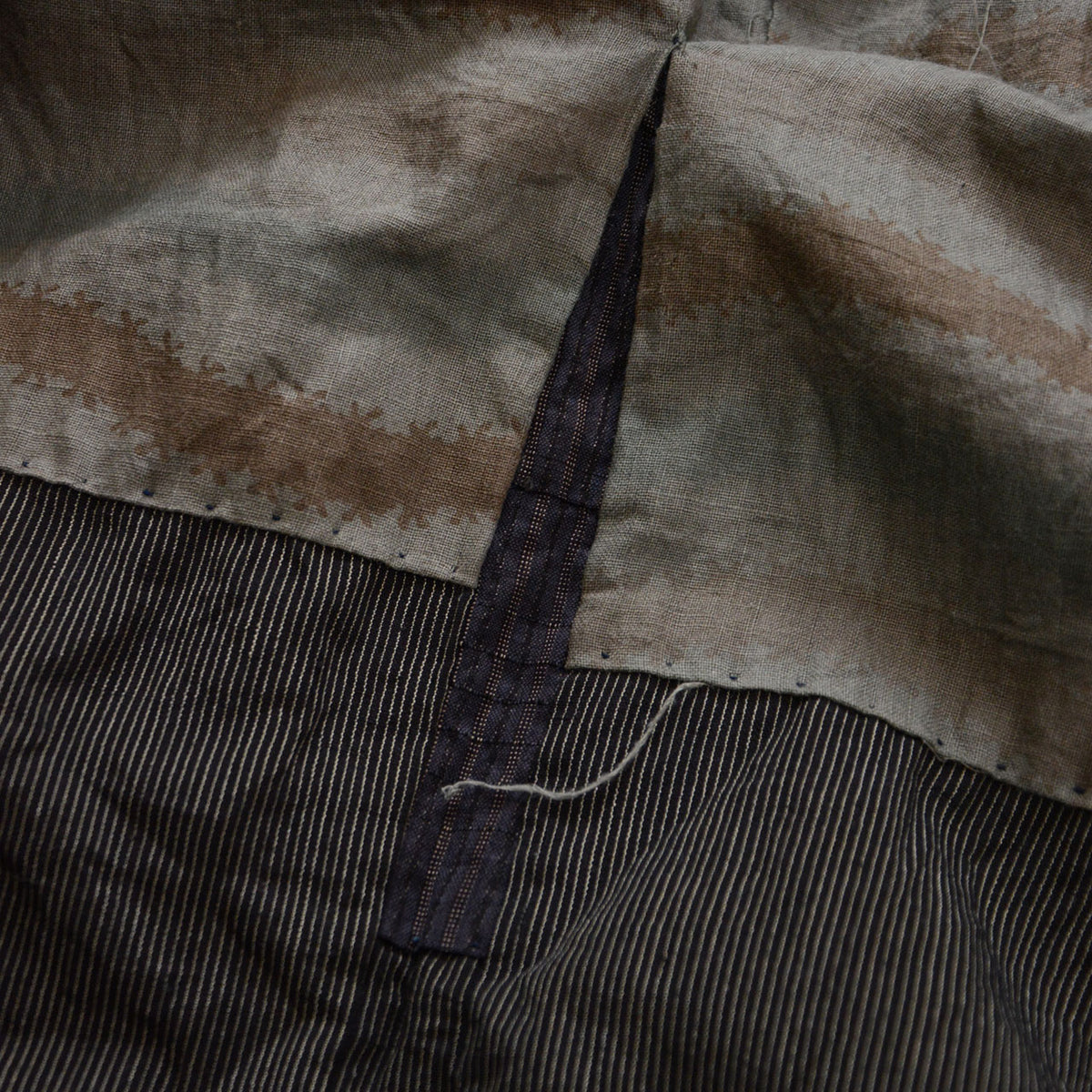 Interior join with a different striped fabric, visible stitches and a loose thread