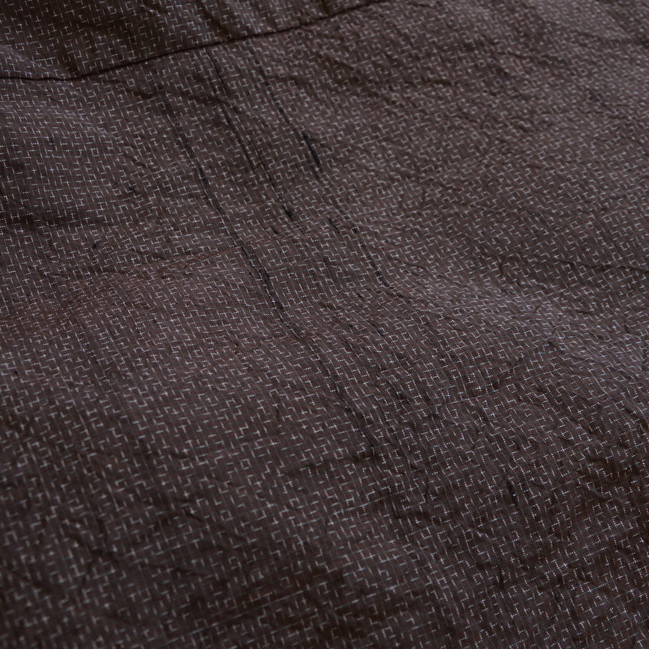 Close-up of dark brown woven fabric — geometric kasuri-style pattern, silk blend, vintage Japanese haori jacket