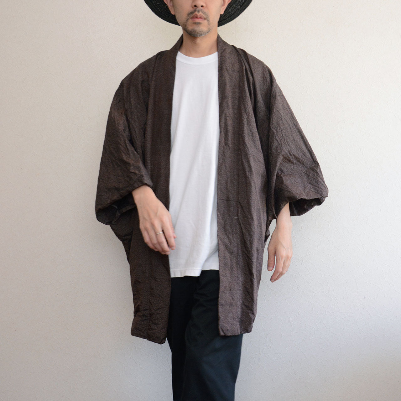 Man wearing a dark brown vintage Japanese haori jacket over a white t-shirt and black jeans — front view, open collar, wide sleeves, 1970s–1980s Japan