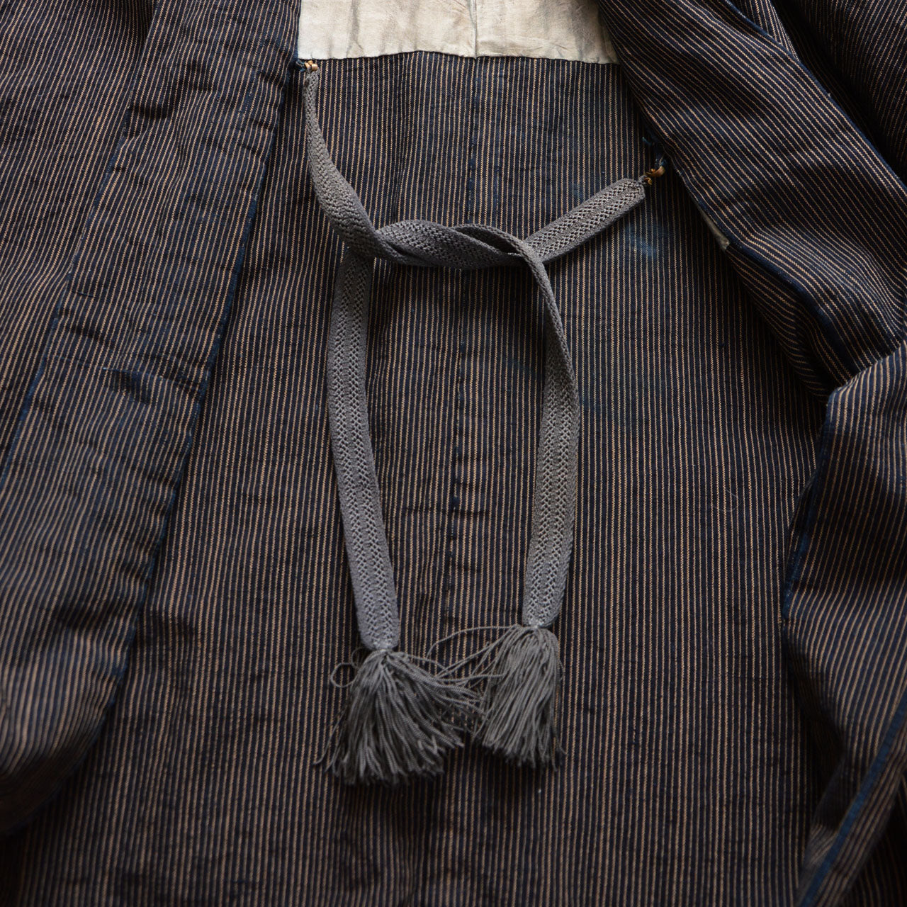 Gray braided haori cord with tassels on indigo striped cotton fabric