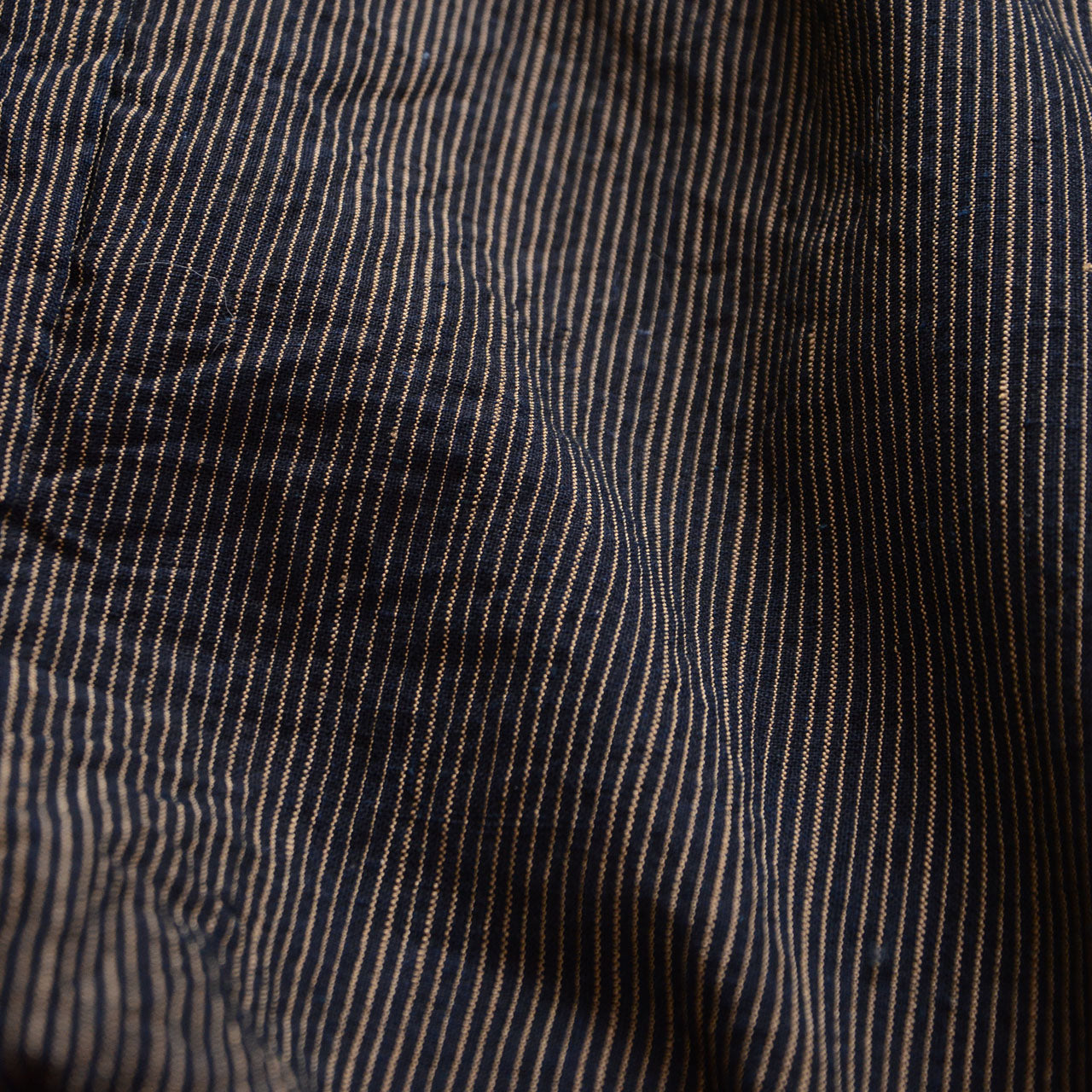 Close-up of fine indigo stripes and woven cotton texture on a vintage haori jacket