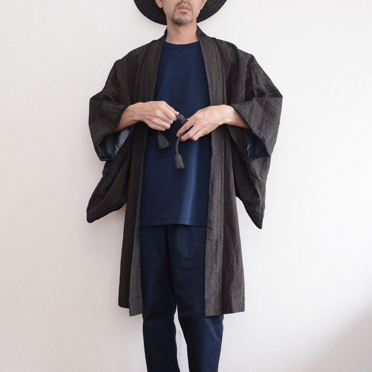 171 cm male model wearing an indigo striped cotton haori and holding its gray cord
