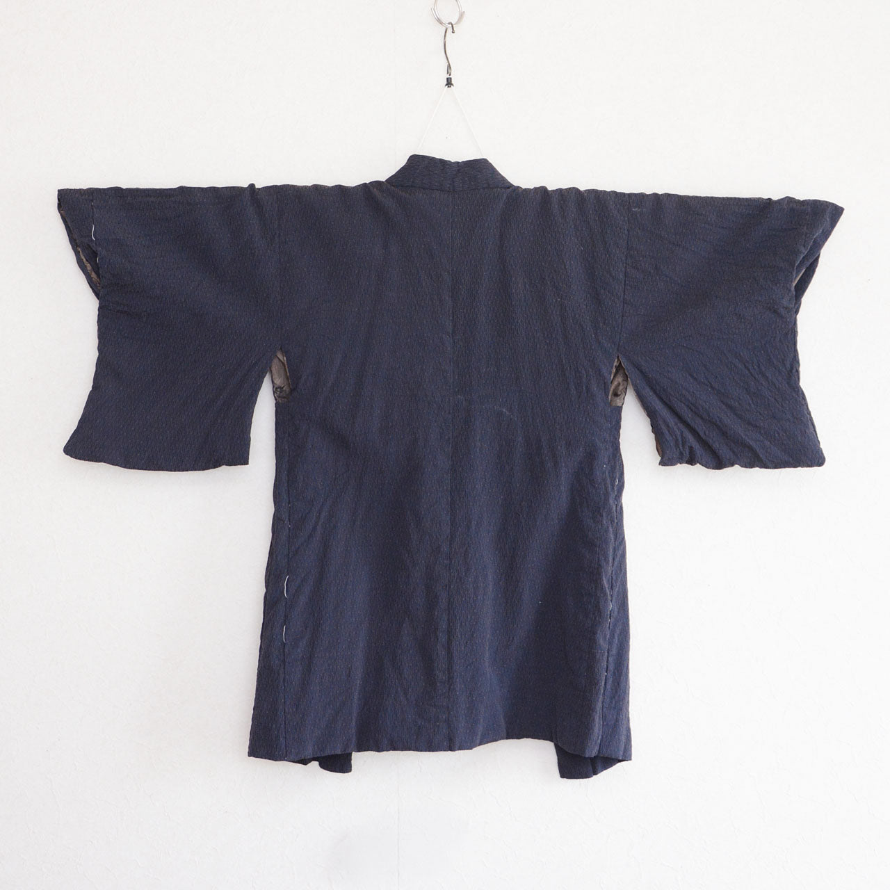 Back view of a deep navy Japanese vintage haori kimono jacket on a kimono hanger, featuring fine raised texture
