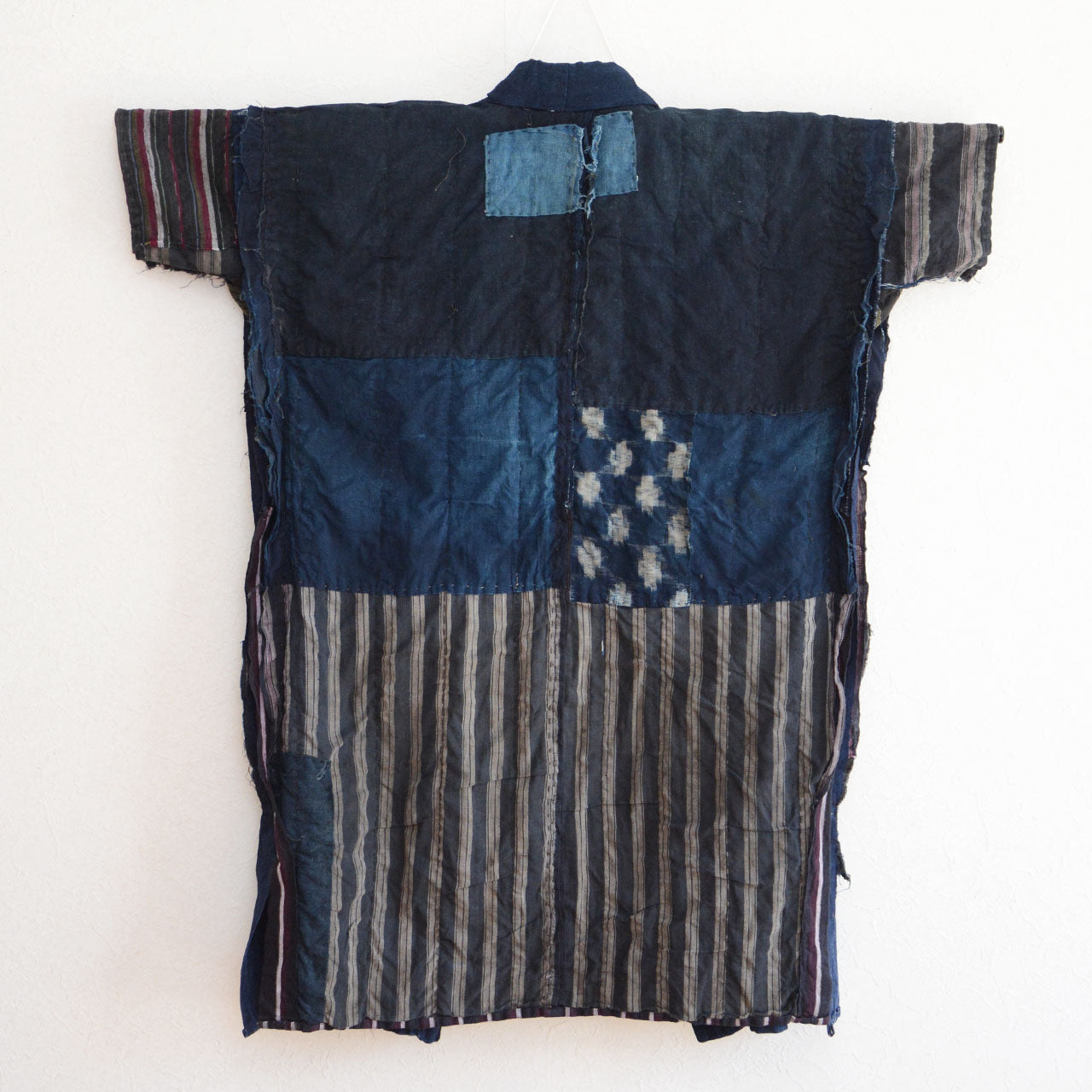 Indigo patchwork noragi with rustic sashiko embroidery and aged texture.