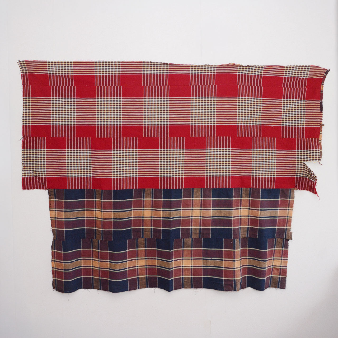 Full front view of vintage Japanese futon cover displayed on wall — crazy pattern with red plaid upper half and navy plaid lower half, mid-Showa era cotton textile