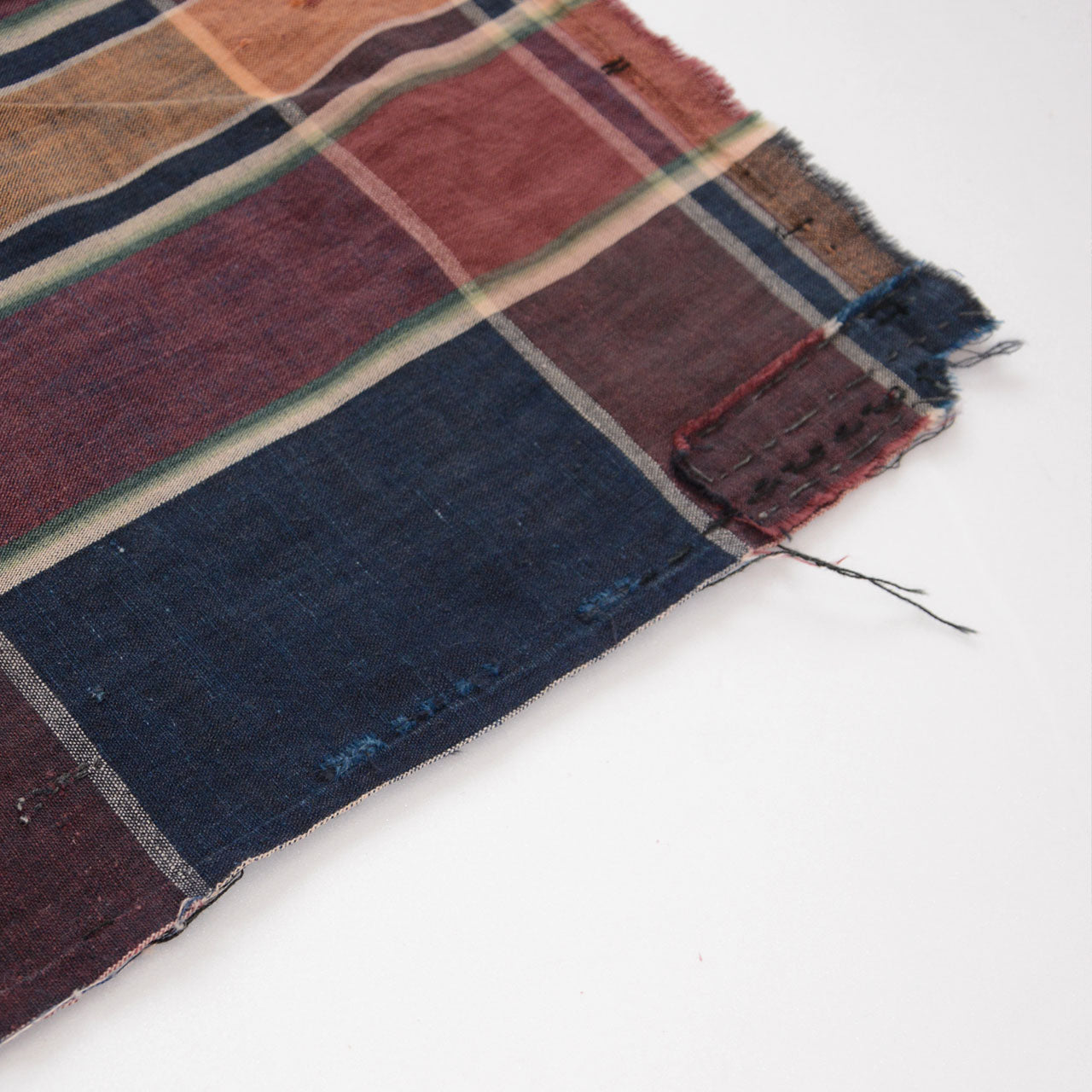 Boro patch repair alongside indigo-dyed section with visible damage — aged cotton futon cover showing wear and hand-stitched mending, Japan vintage textile