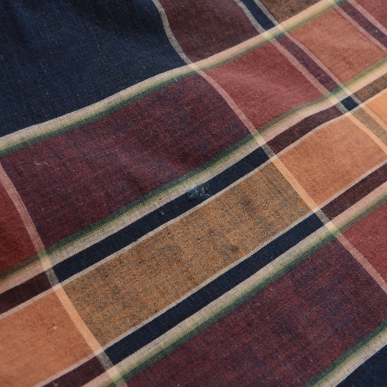 Close-up of fabric surface showing damage — aged cotton weave with wear marks and distress, vintage Japanese futon cover textile detail