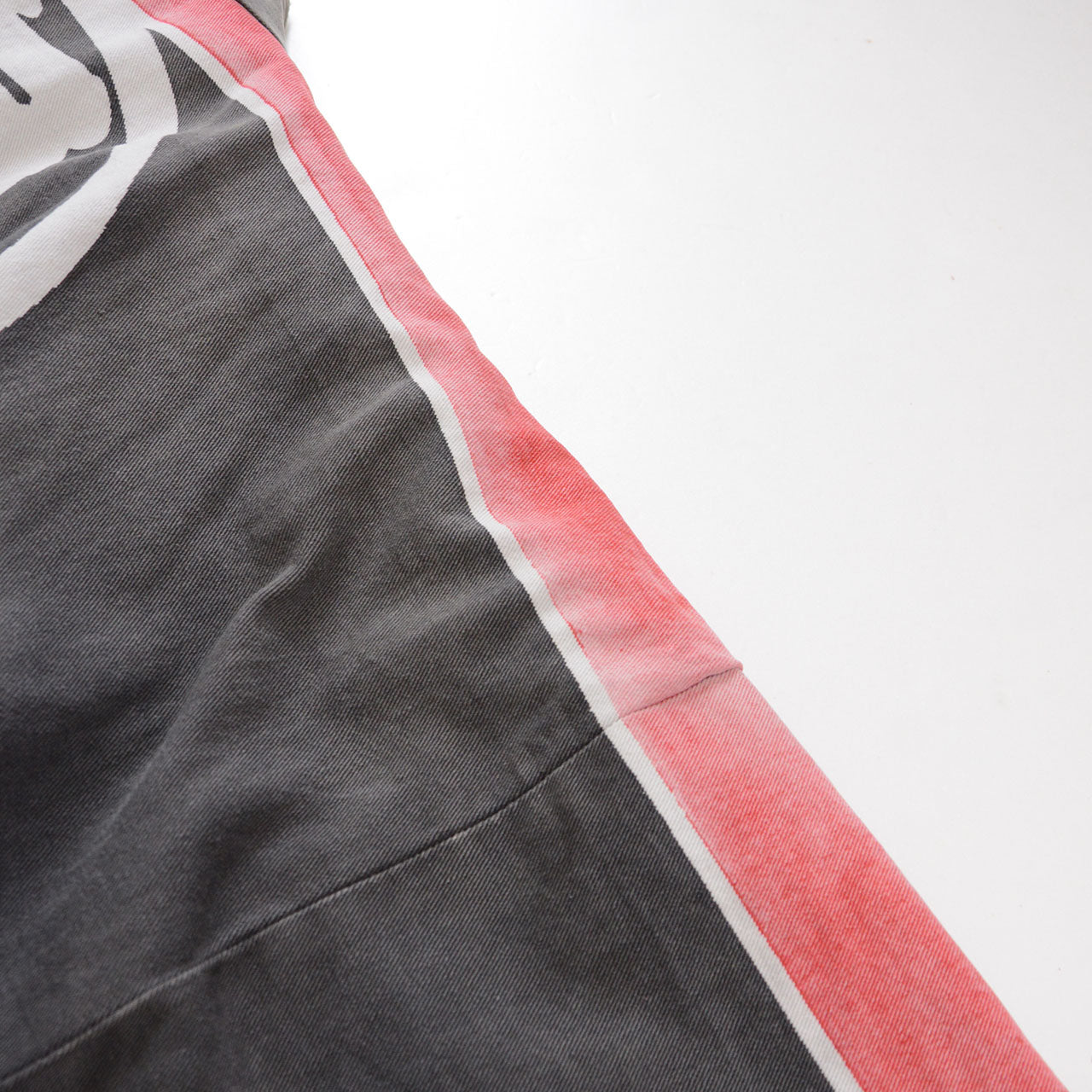 Close-up of the faded red and white shoulder stripe on a charcoal-gray cotton Japanese firefighter happi jacket