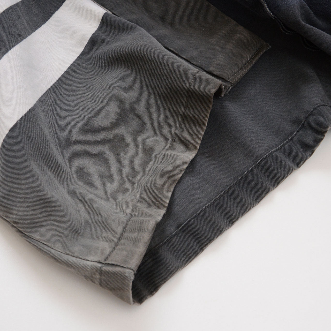 Hem and white horizontal stripe on a faded charcoal-gray cotton Japanese firefighter happi jacket