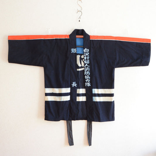 Vintage Japanese firefighter happi coat displayed on a traditional kimono hanger, front view