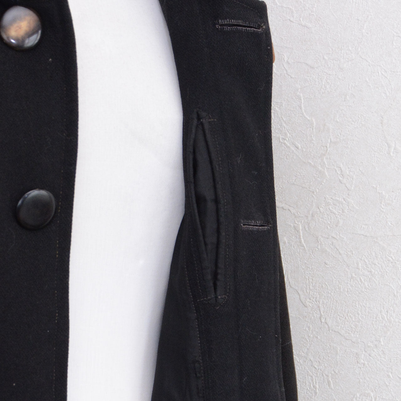 Concealed pocket set into the button placket of a black wool Bankara mantle.