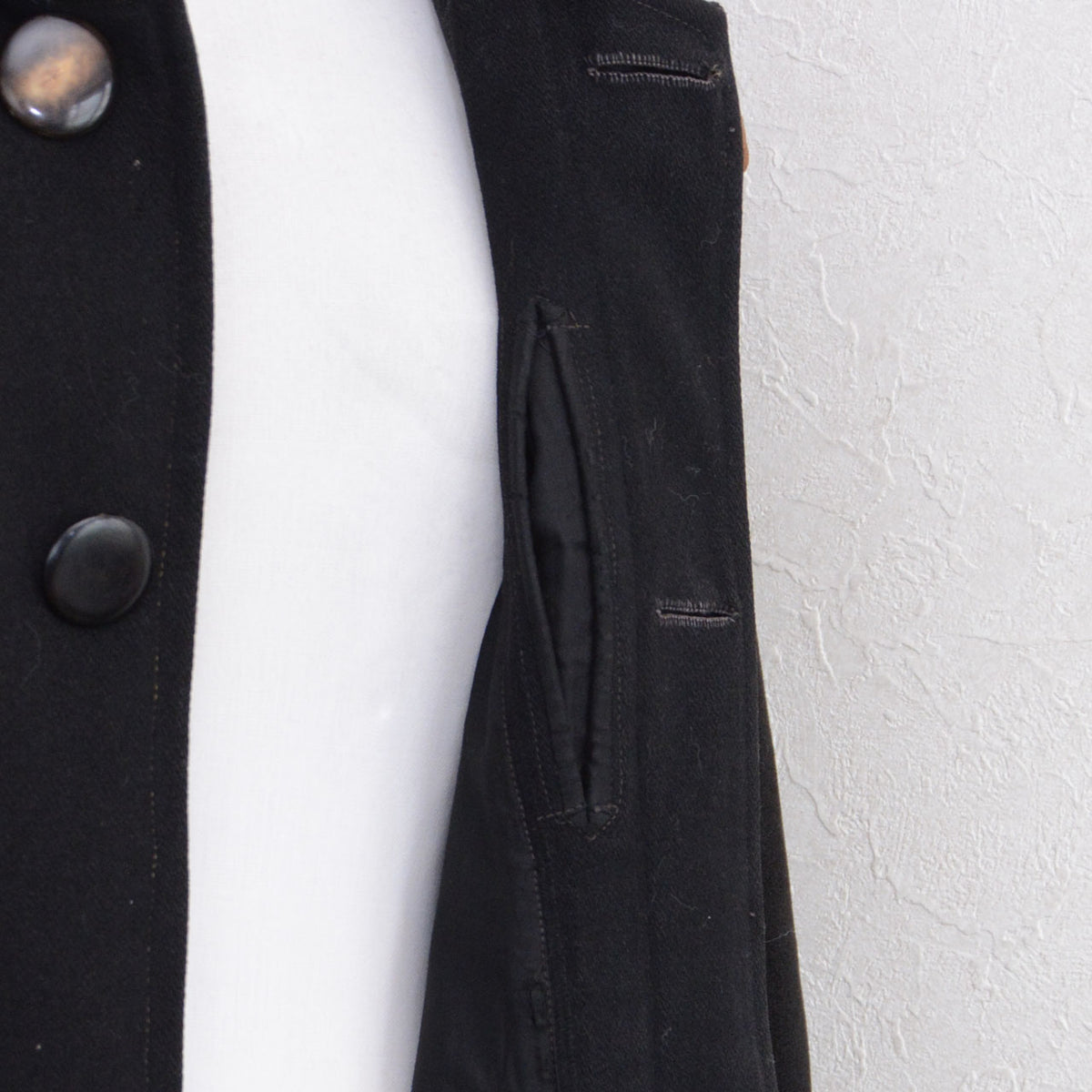 Concealed pocket set into the button placket of a black wool Bankara mantle.