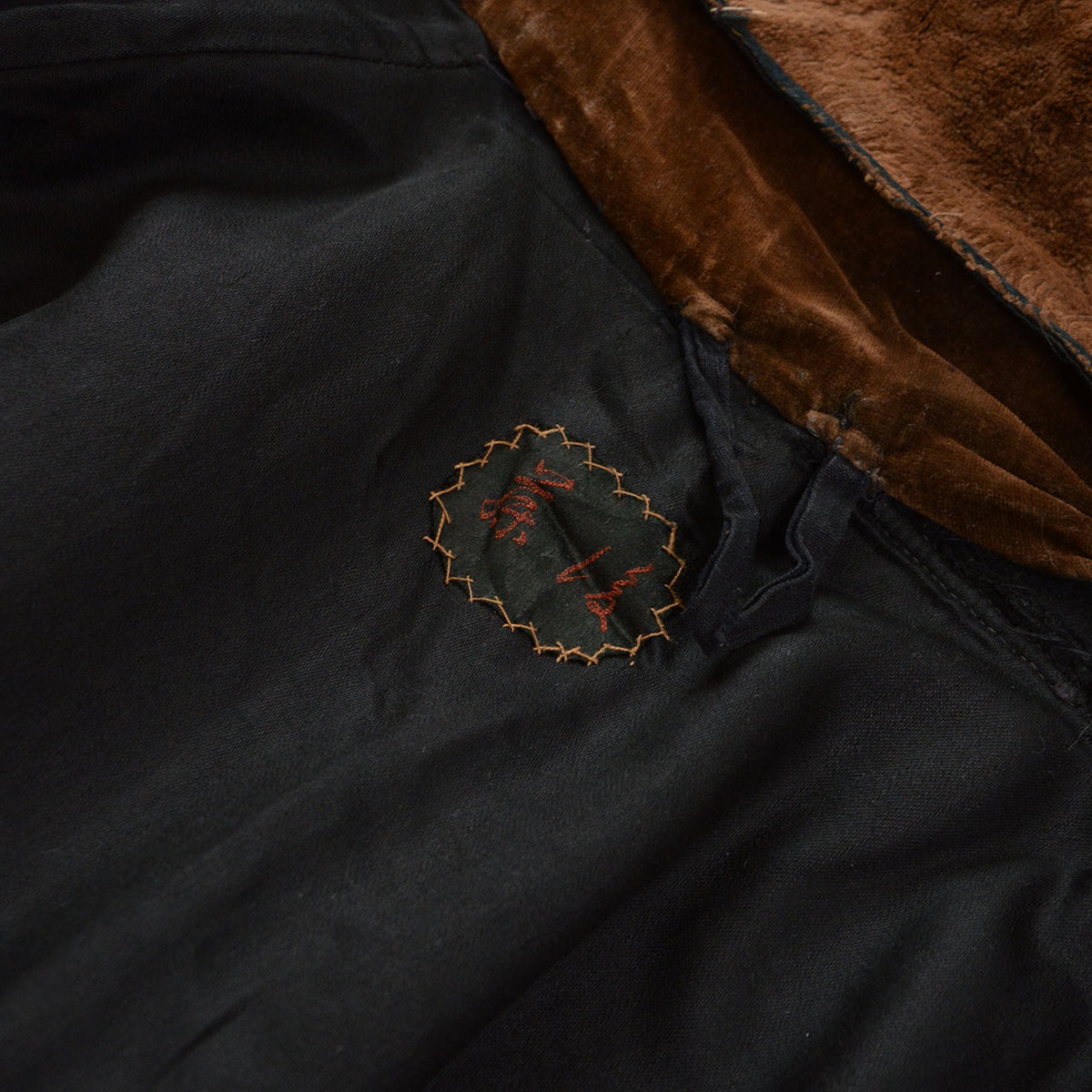Interior name embroidery in an older Japanese right-to-left format on a black wool mantle.