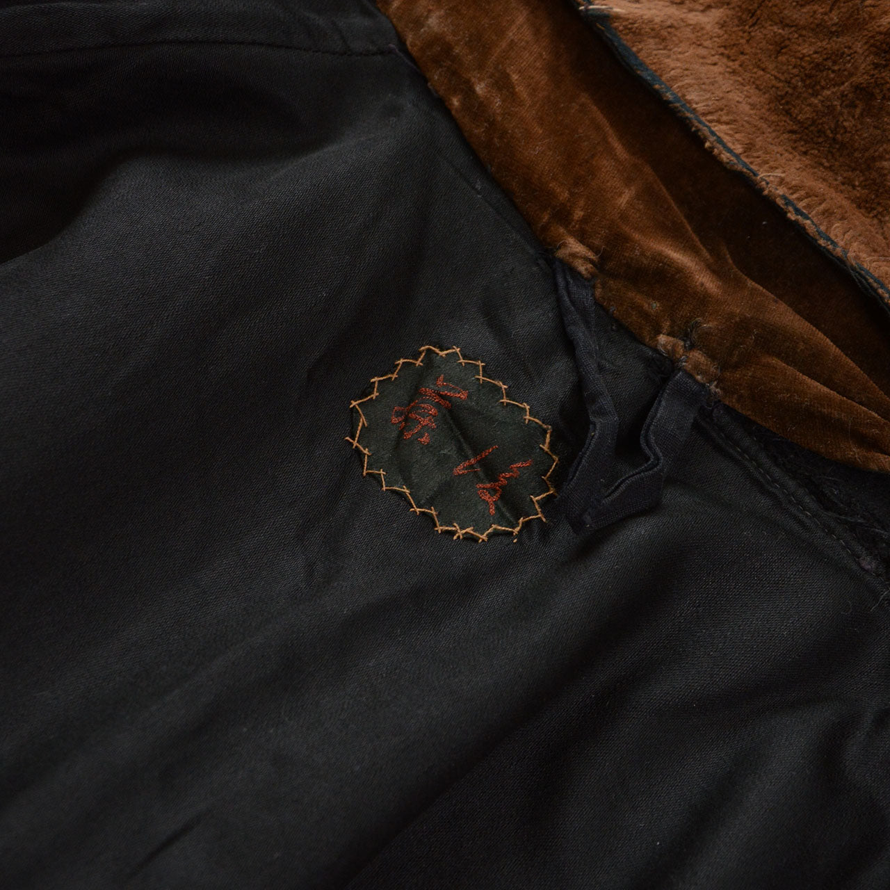 Interior name embroidery in an older Japanese right-to-left format on a black wool mantle.