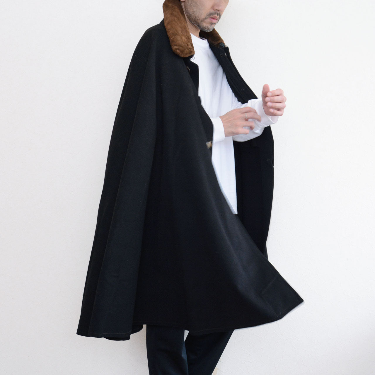 Model wearing a black Bankara mantle with brown fur collar and front buttons.
