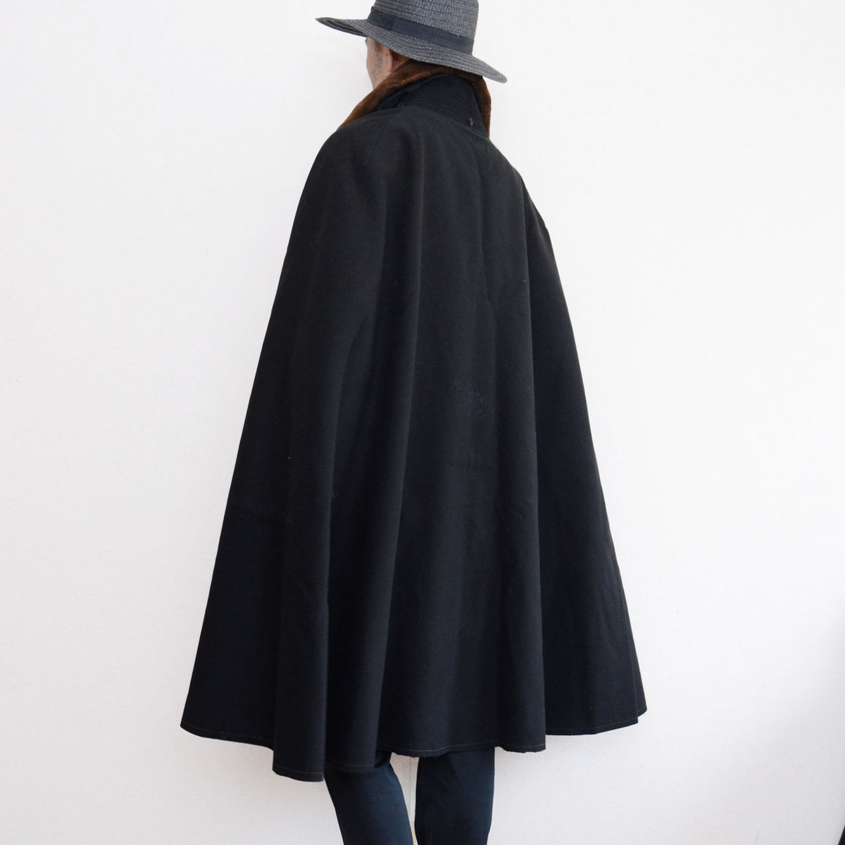 Model wearing a black Bankara mantle with a broad draped rear silhouette and brown fur collar.