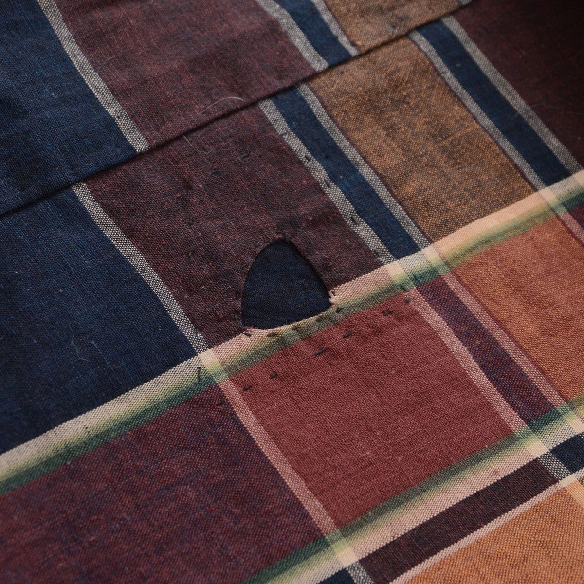 Indigo patch repair on brown, red-brown, and indigo checkered Japanese vintage cotton fabric