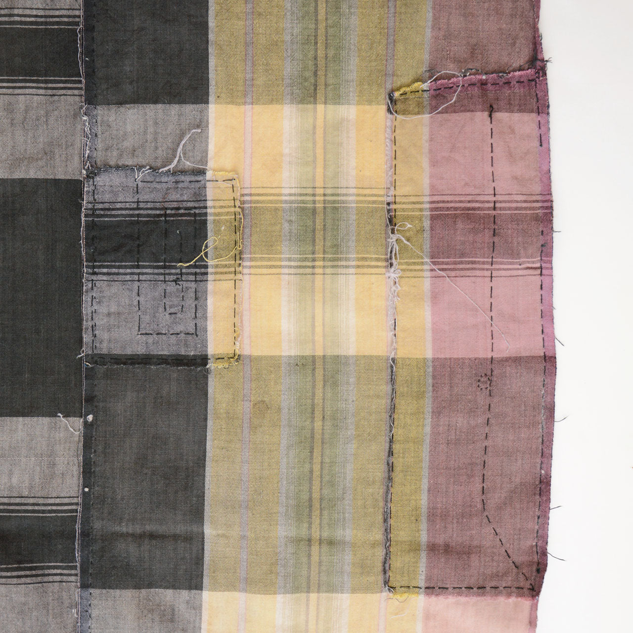 Japanese vintage cotton plaid fabric, multiple hand-sewn boro patches along edge, running stitch detail, Showa era