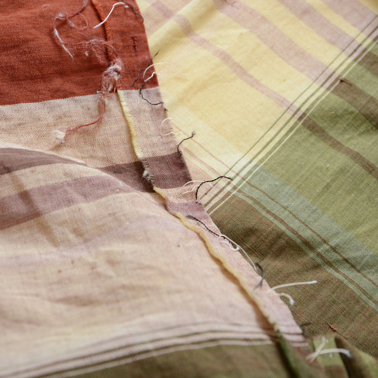 Japanese vintage cotton fabric, olive green plaid with brown and cream stripes, unstitched Showa-era futon textile, loose threads and needle holes along seam line