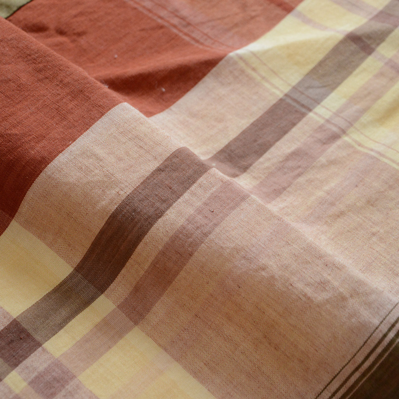 Japanese vintage cotton fabric, rust red and cream plaid, unstitched Showa-era futon textile, soft drape showing woven stripe detail and aged cotton texture