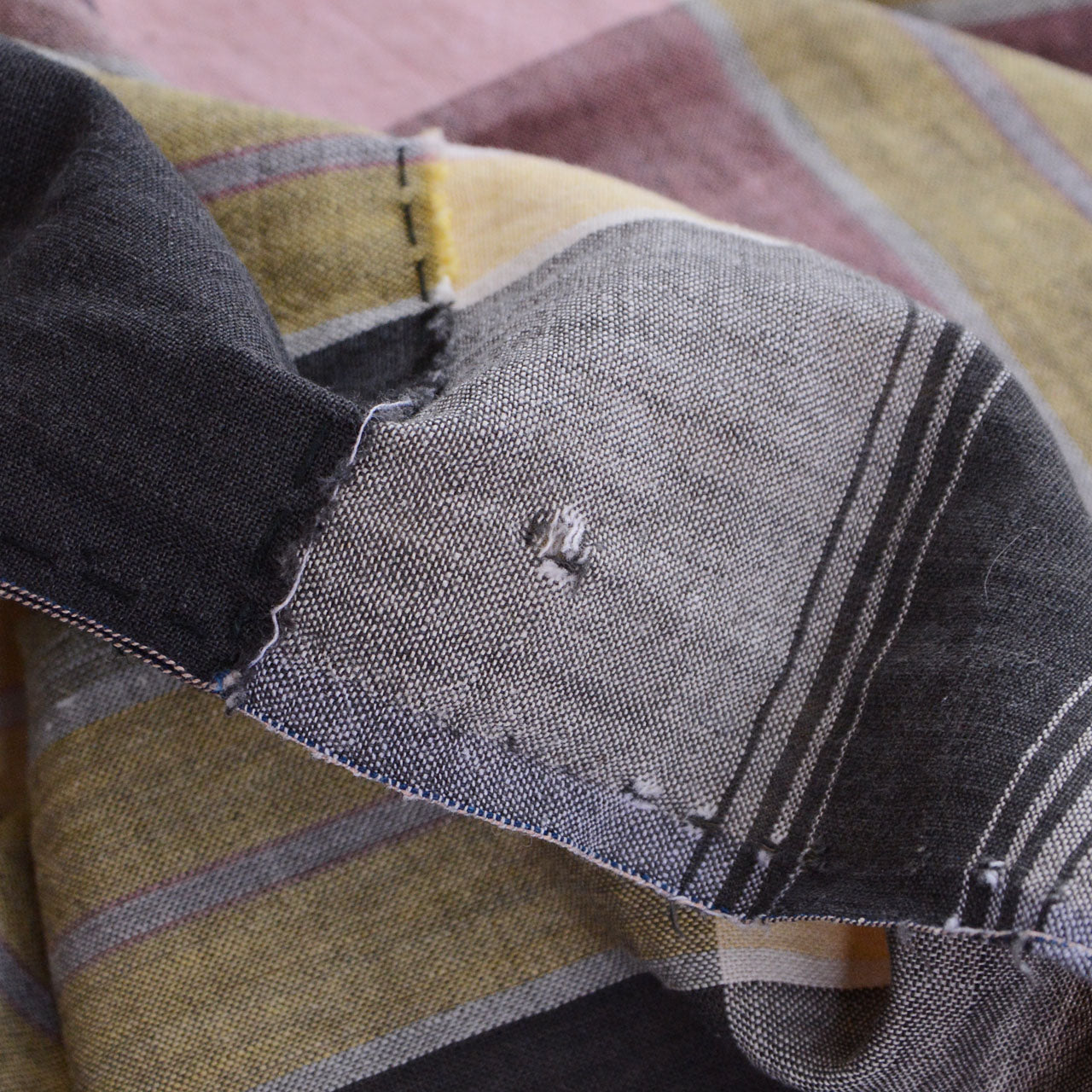 Hole in vintage Japanese cotton fabric — visible wear from decades of use, part of its authentic boro character