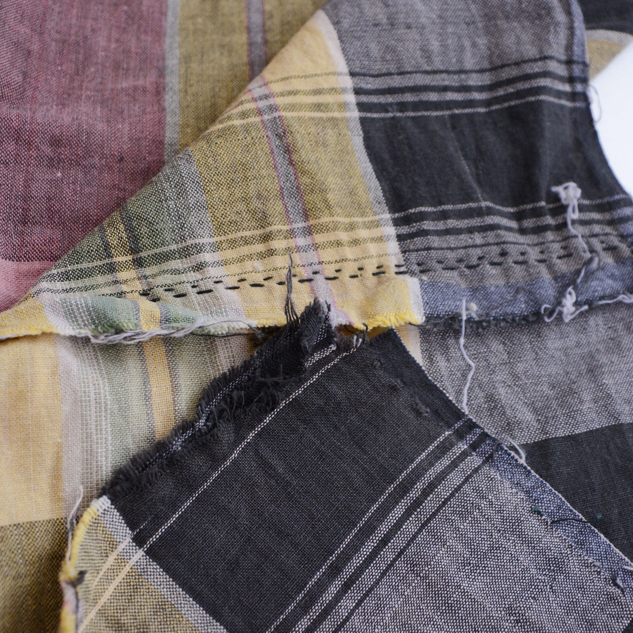 Hand-stitching and frayed edge detail on vintage Japanese cotton fabric — labor-intensive seam work done entirely by hand