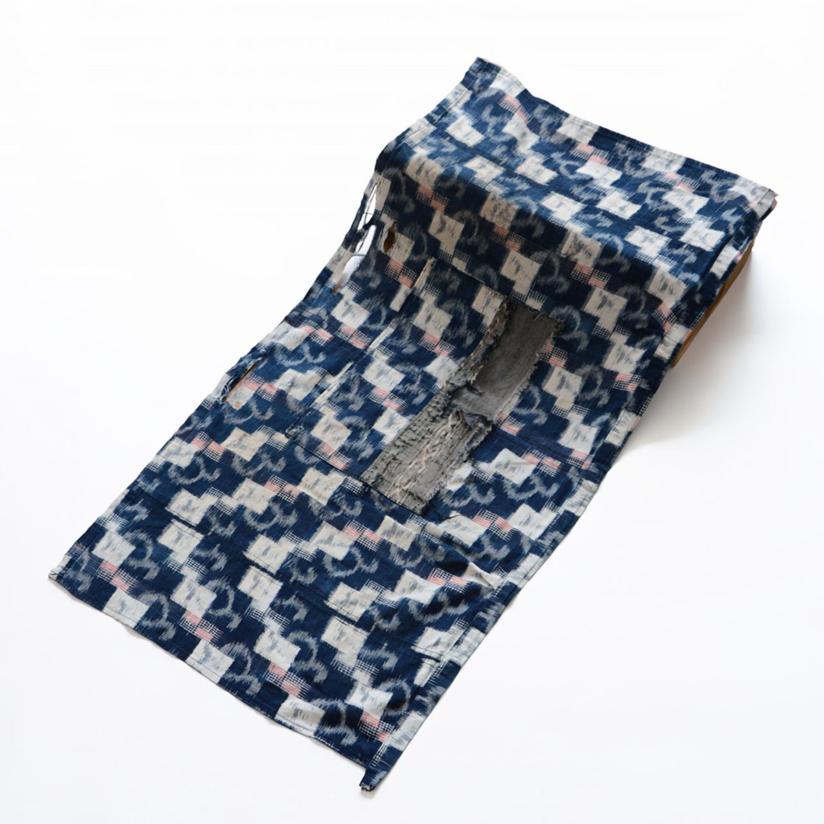 Japanese vintage indigo kasuri cotton textile from the mid-Showa period with white geometric motifs, red accents and a central pocket
