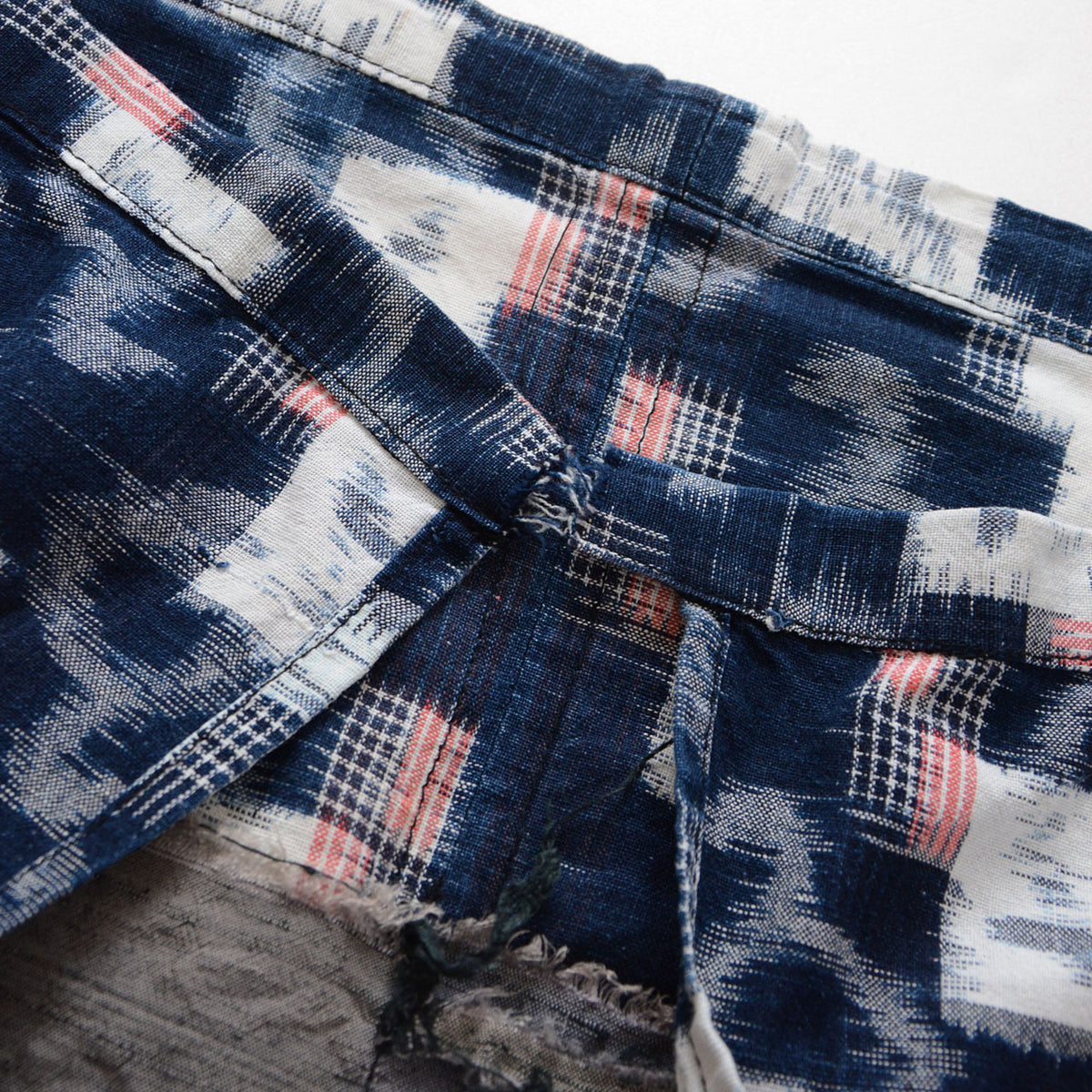 Japanese vintage indigo cotton fabric with white kasuri motifs, fine red lines and fraying where the apron ties were cut off