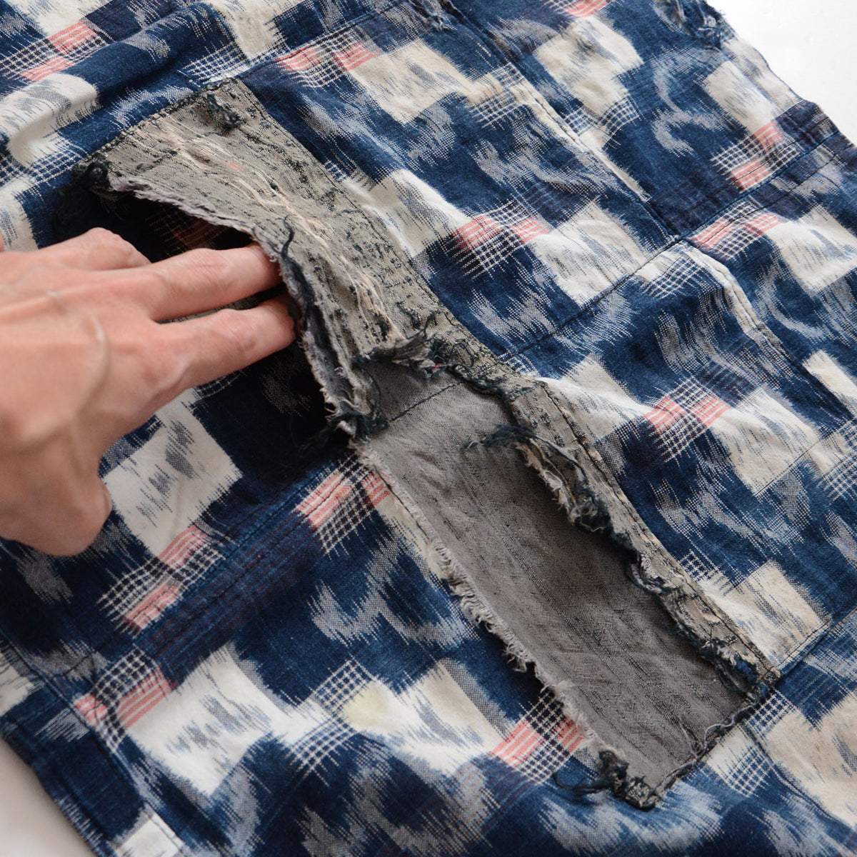 Mid-Showa indigo kasuri cotton fabric with white and red motifs and missing fabric and fraying in the central pocket