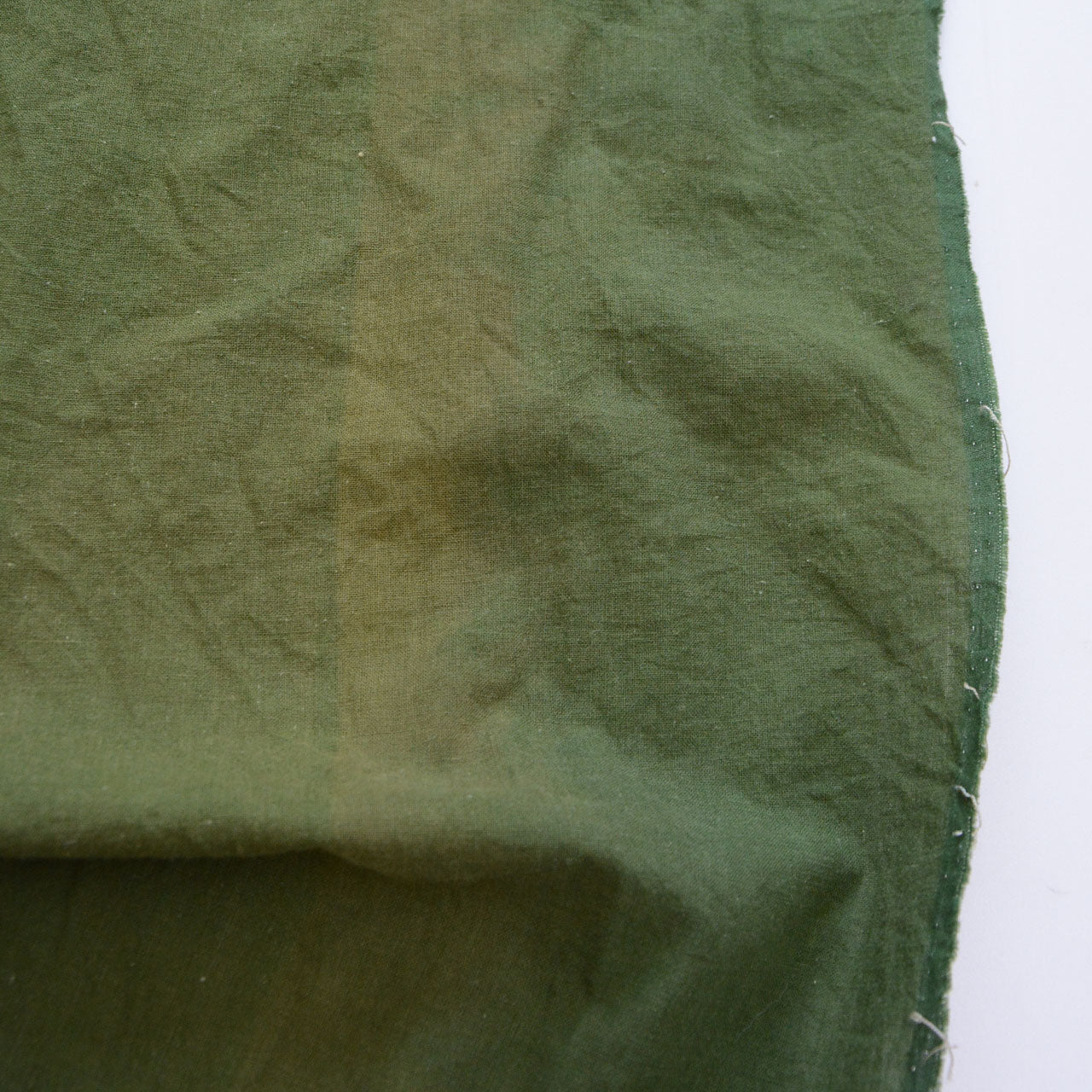 Showa-era Japanese vintage cotton fabric, solid moss green, close-up of naturally faded section, rich texture and depth of aged cotton, boro material