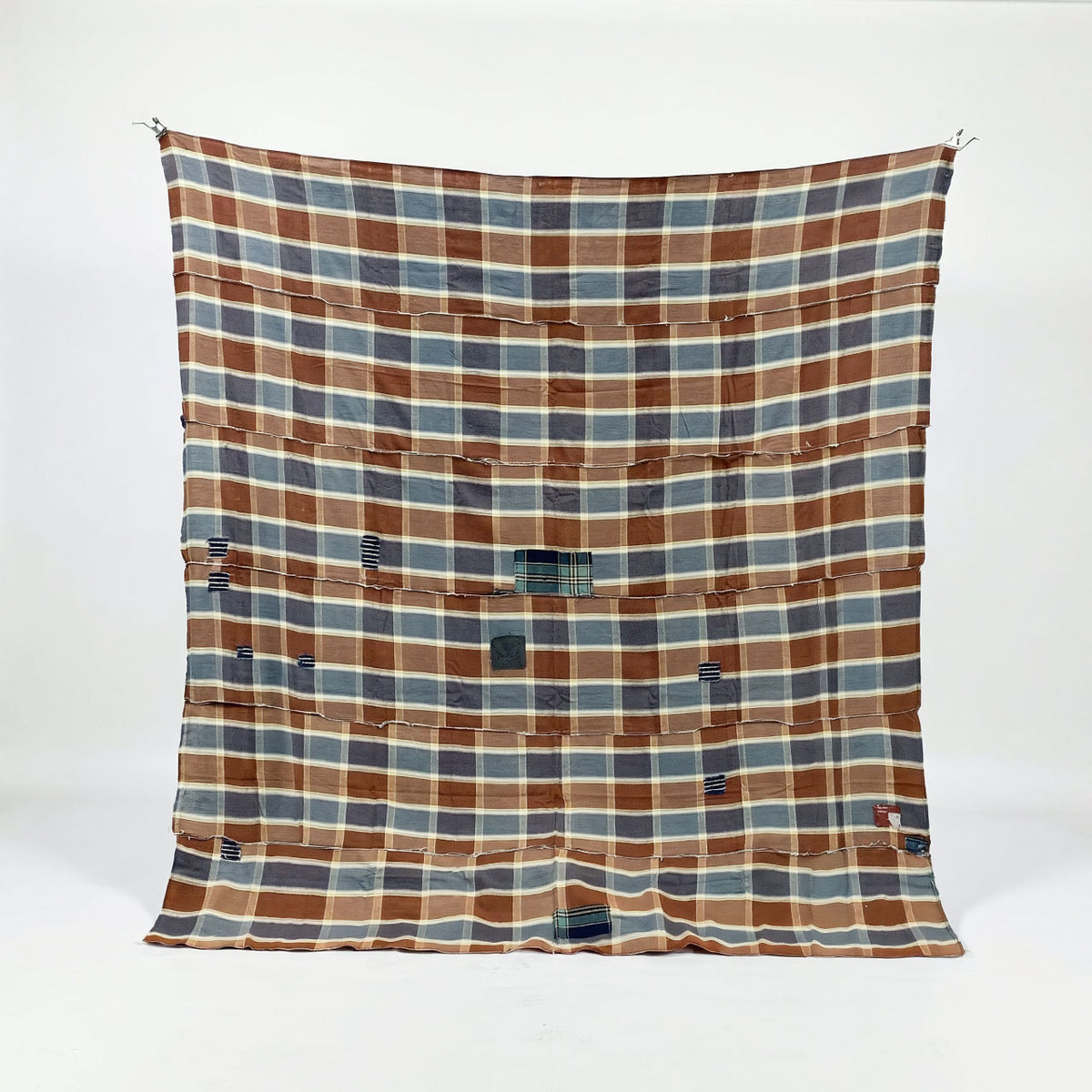Unstitched Japanese vintage cotton fabric with a large brown, blue-gray, and cream checkered pattern and multiple repair patches
