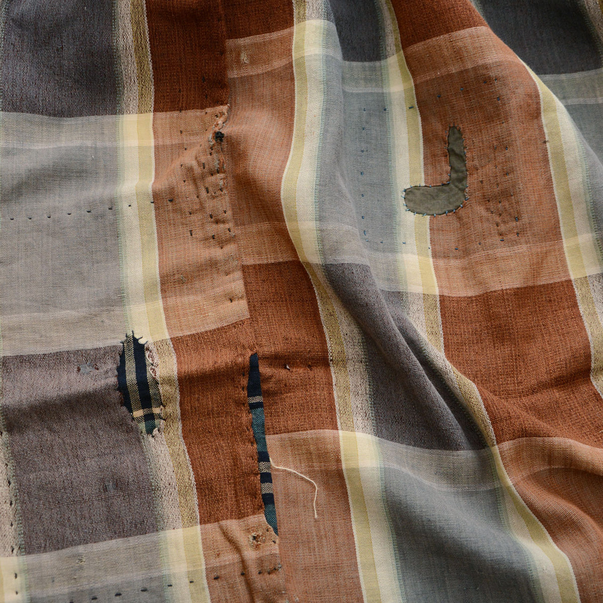 Japanese vintage cotton fabric with checkered pattern, exposed weave, fraying, missing areas, and patch repairs