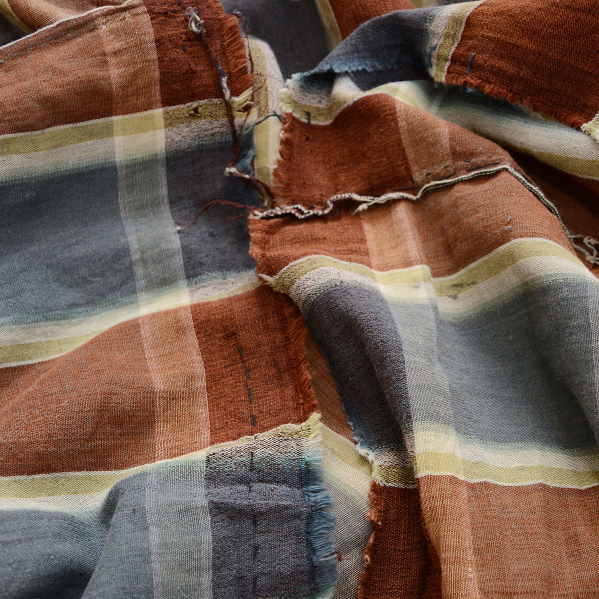 Brown, blue-gray, and cream checkered Japanese vintage cotton fabric with frayed edges, missing stitches, and boro repairs
