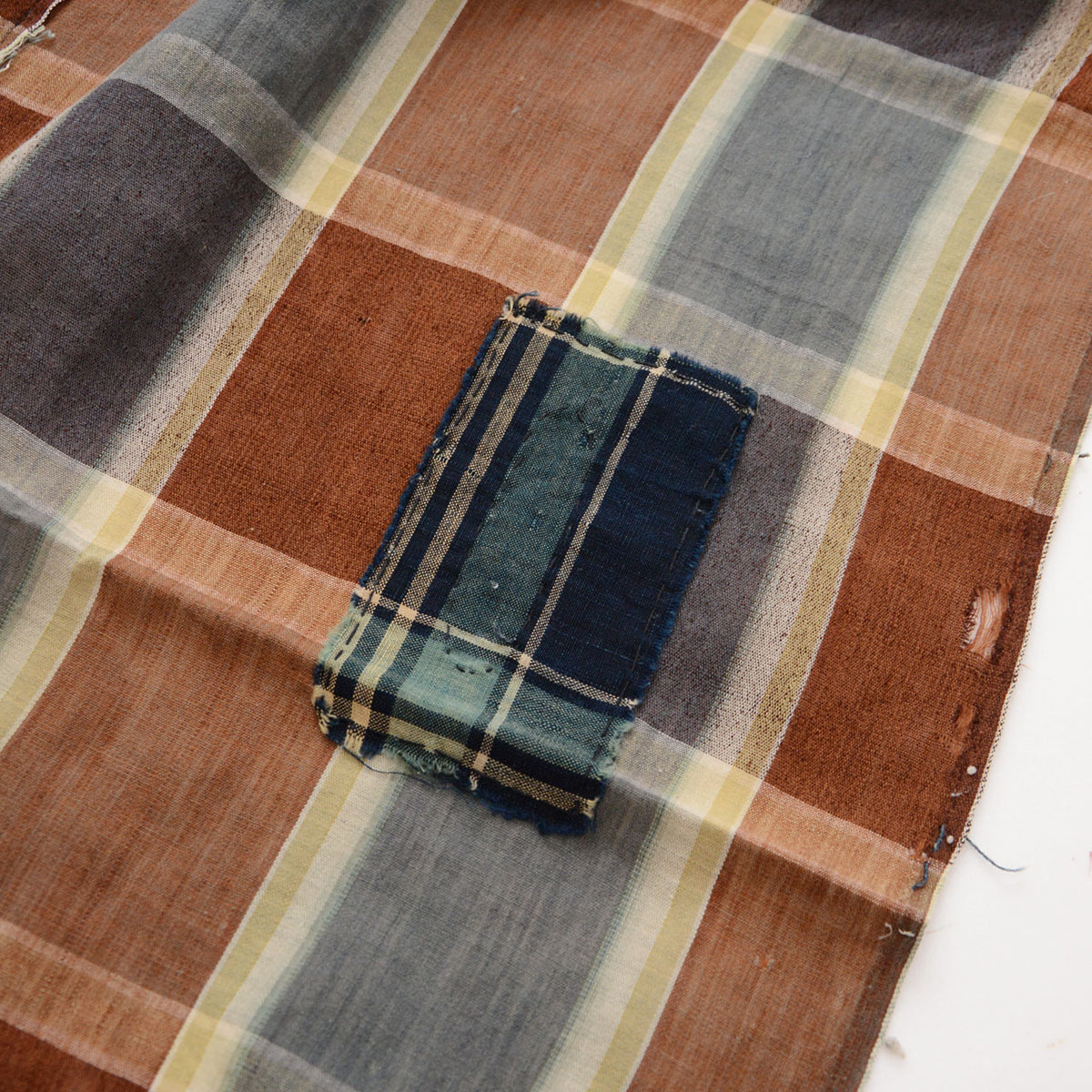 Japanese vintage checkered cotton fabric with several dark blue, teal, and striped boro repair patches