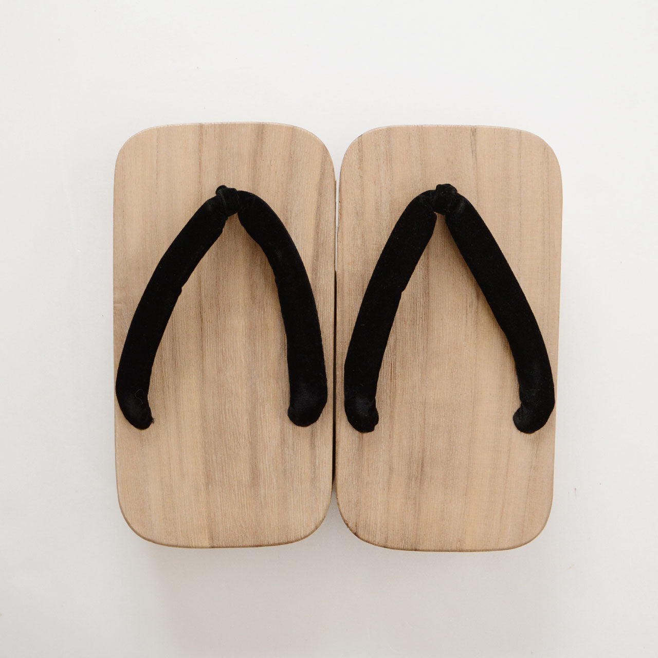 Top surface of Aizu Paulownia geta with knotted black hanao thong, shot from directly above