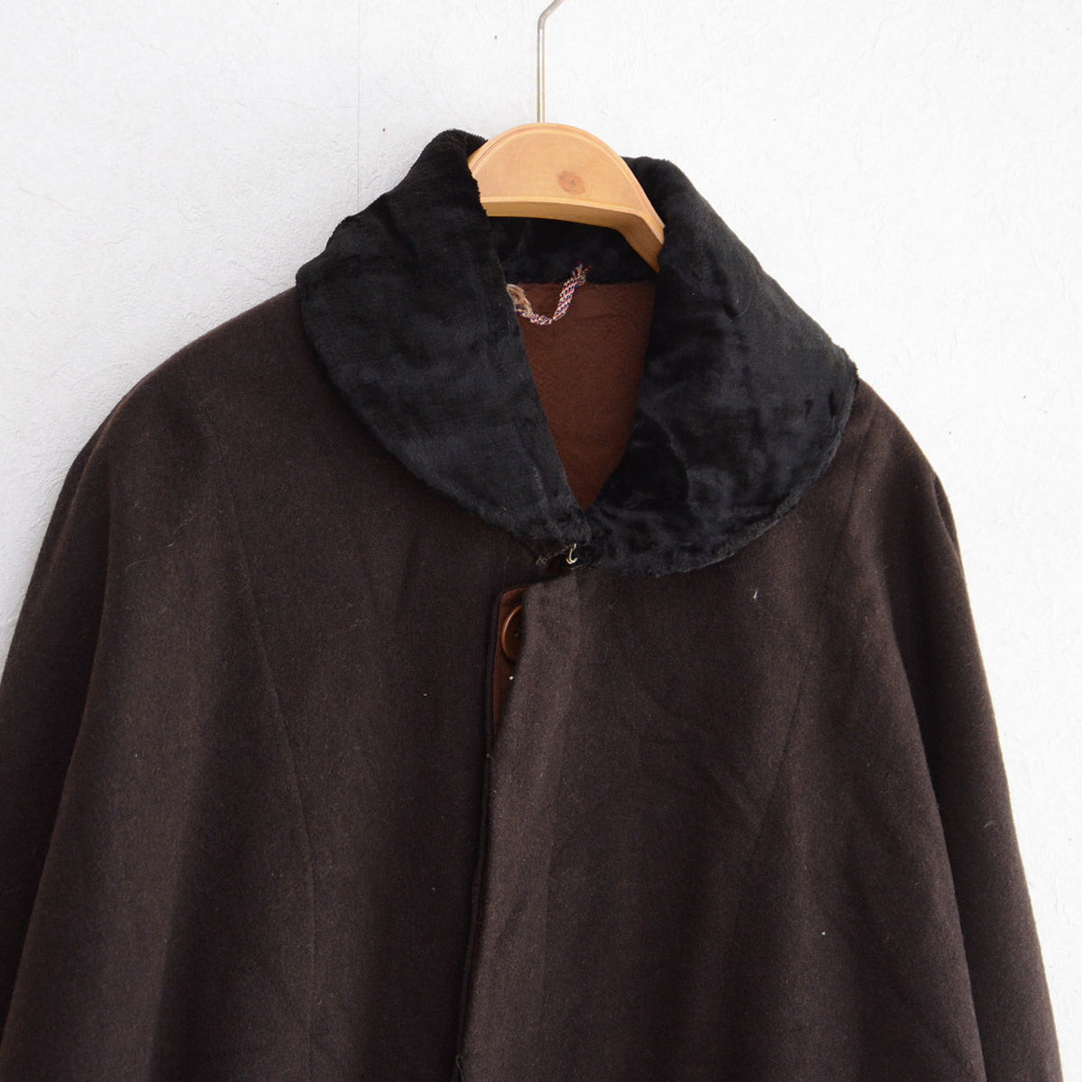 Black textured collar and neckline fastening on a dark brown vintage mantle