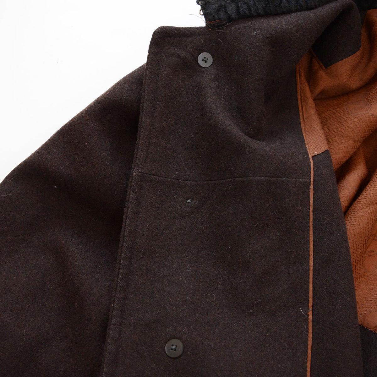Inner button fastenings on a dark brown vintage mantle, with one fastening missing