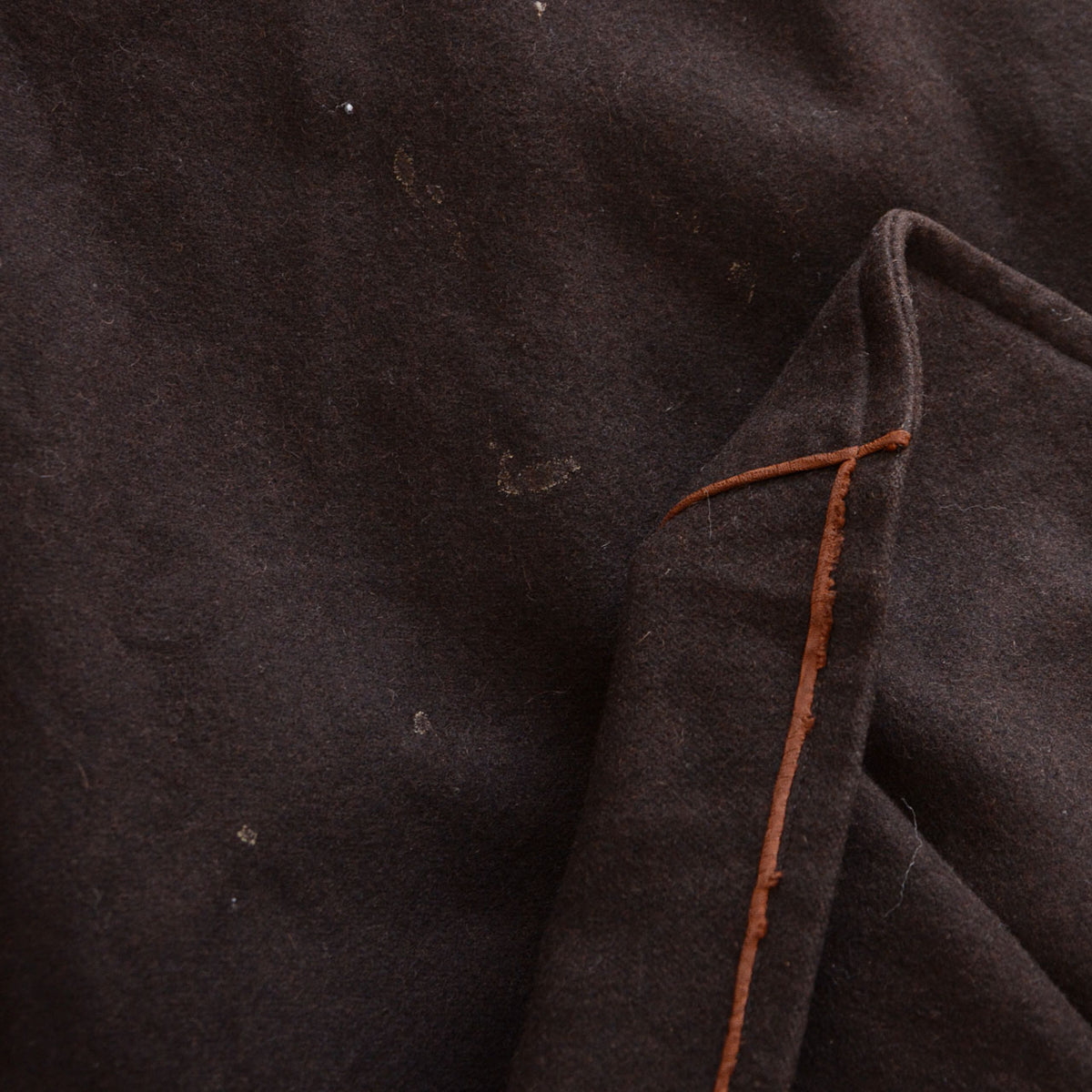 Stains and damaged brown piping on a dark brown vintage mantle
