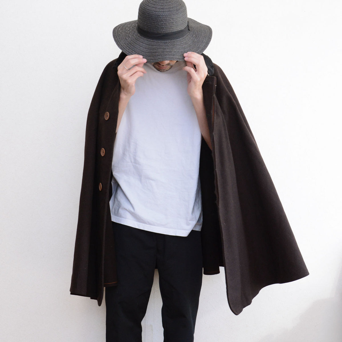Dark brown Japanese vintage mantle with a white top, black trousers and dark hat