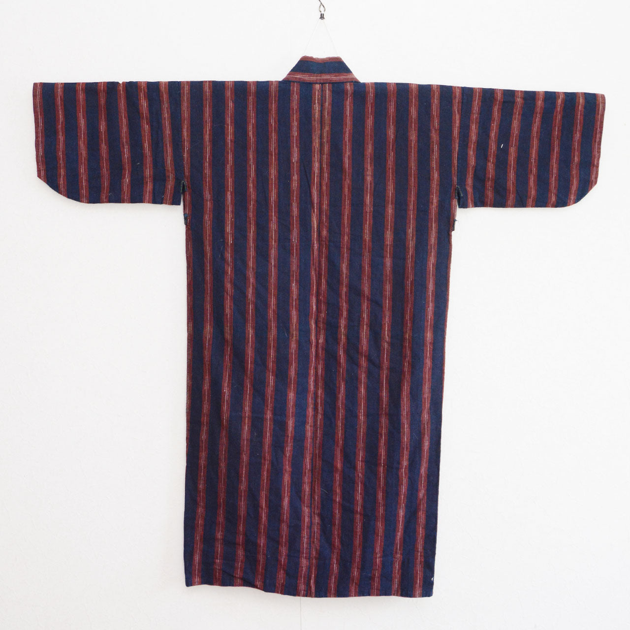 Vintage noragi jacket on hanger, back view — indigo-dyed cotton with bold red stripe, Tohoku, early Showa era
