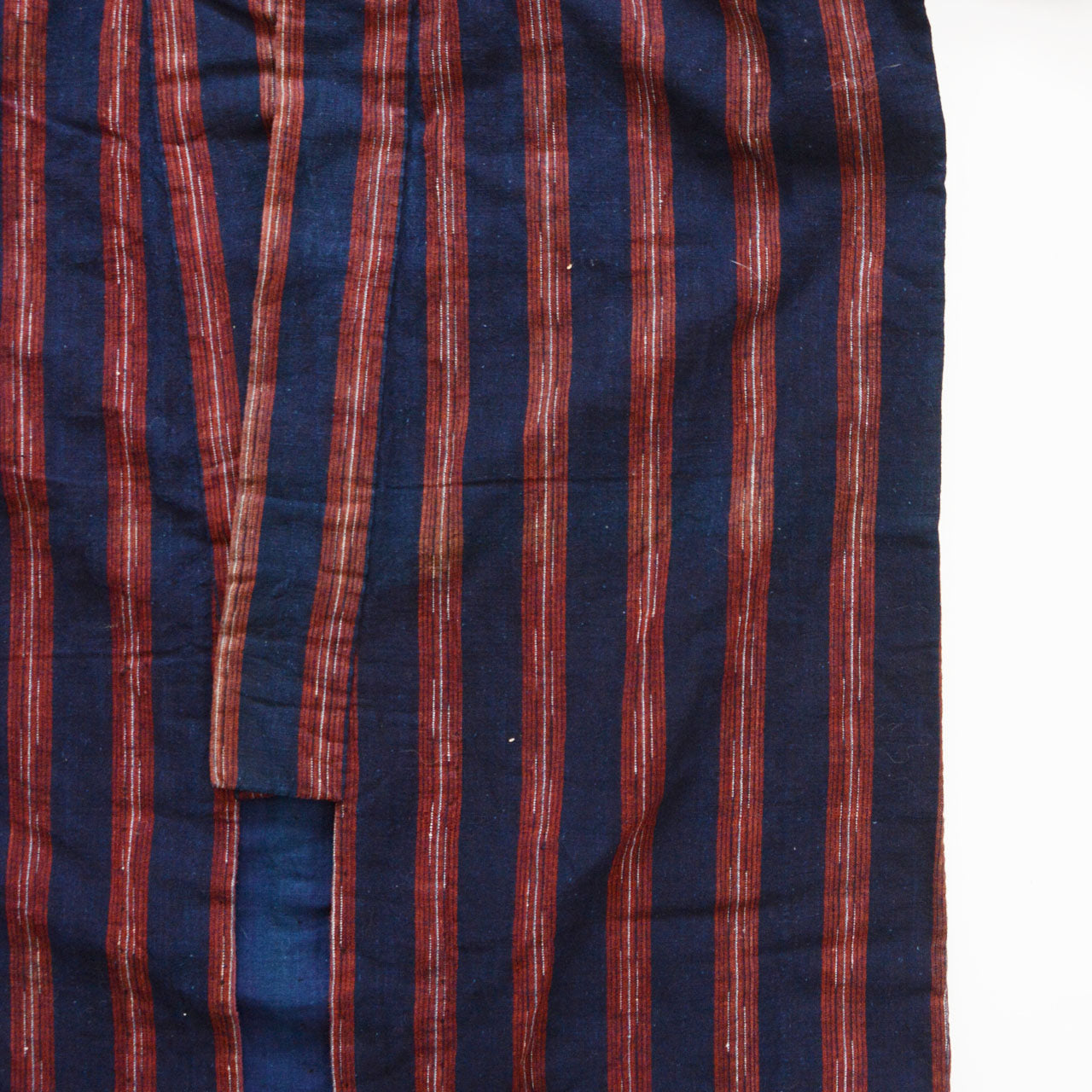 Extreme close-up of indigo-dyed cotton stripe — wide-pitch red stripe with white thread detail, vintage noragi fabric, Tohoku, early Showa era