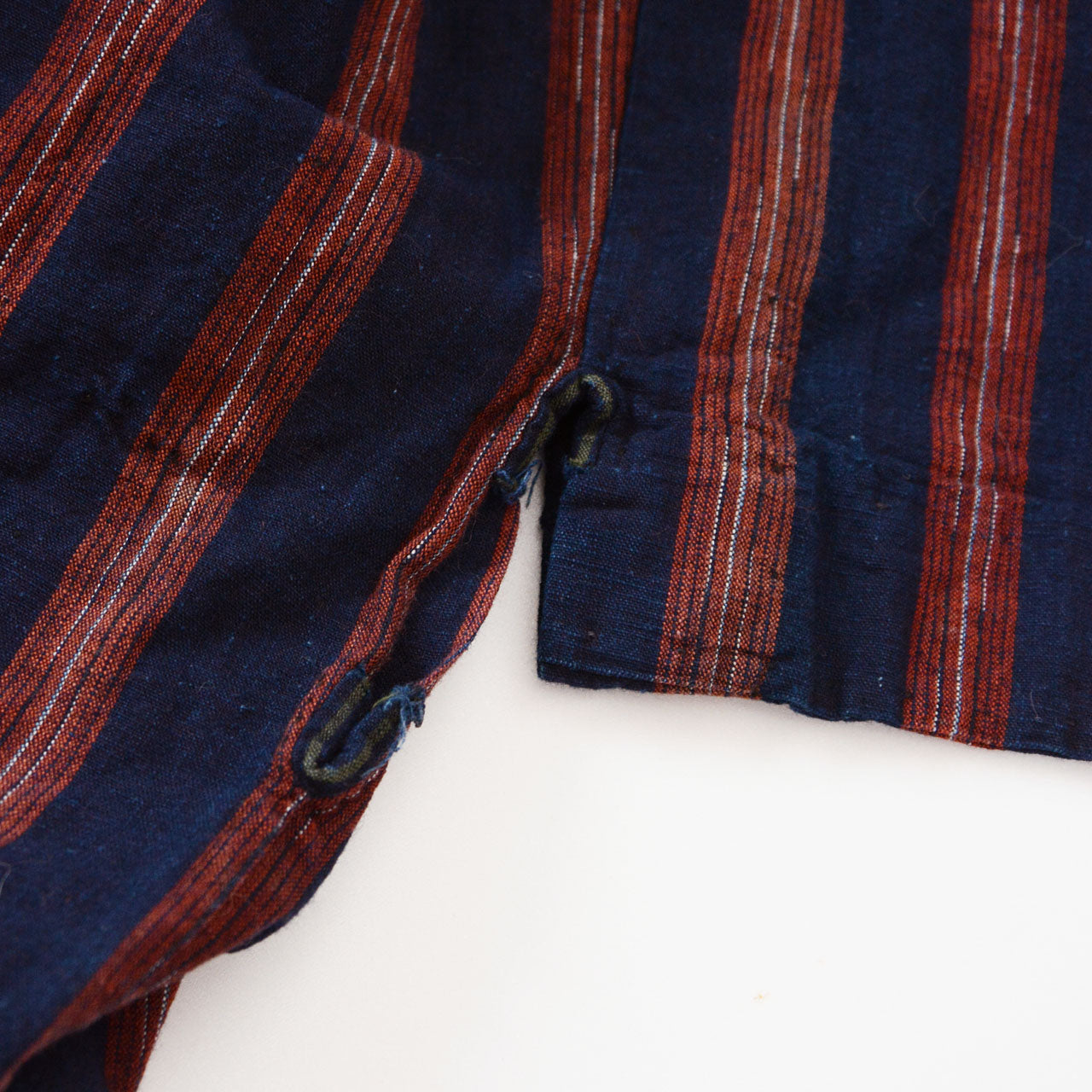 Miyatsuguchi detail of a vintage noragi — side opening at the body seam, indigo-dyed cotton with bold red stripe, early Showa era