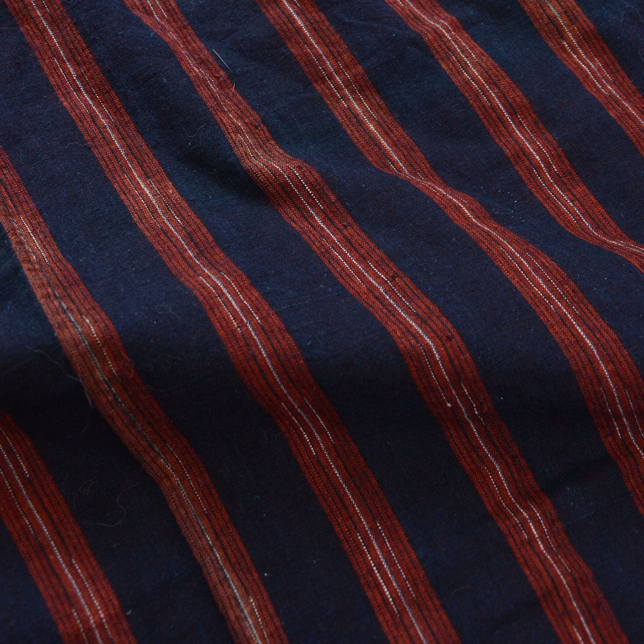 Close-up of indigo-dyed cotton fabric — wide-pitch red stripe with fine thread detail, vintage noragi textile, Tohoku, early Showa era