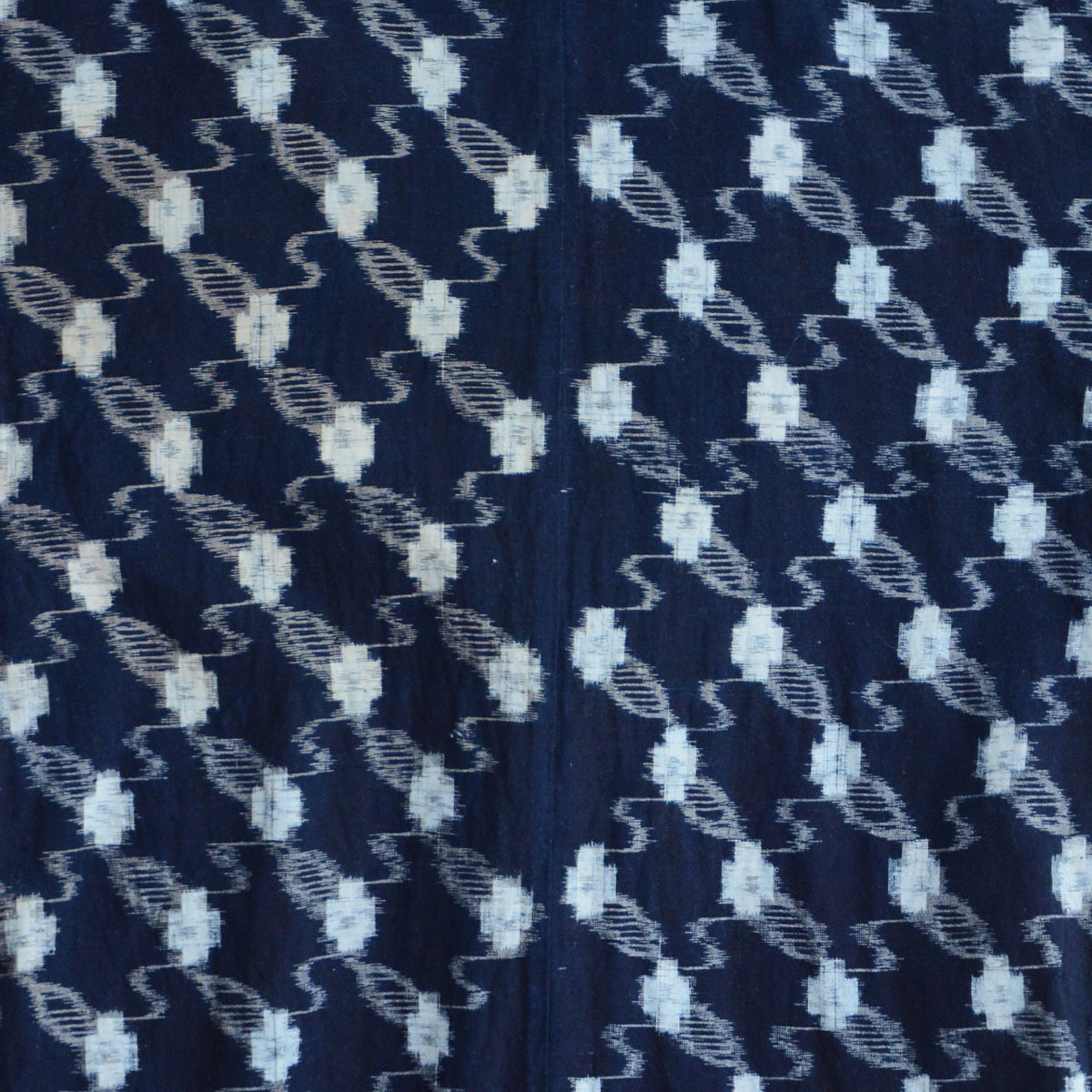 Close-up of indigo kasuri cotton fabric showing the full repeating pattern with a vertical seam