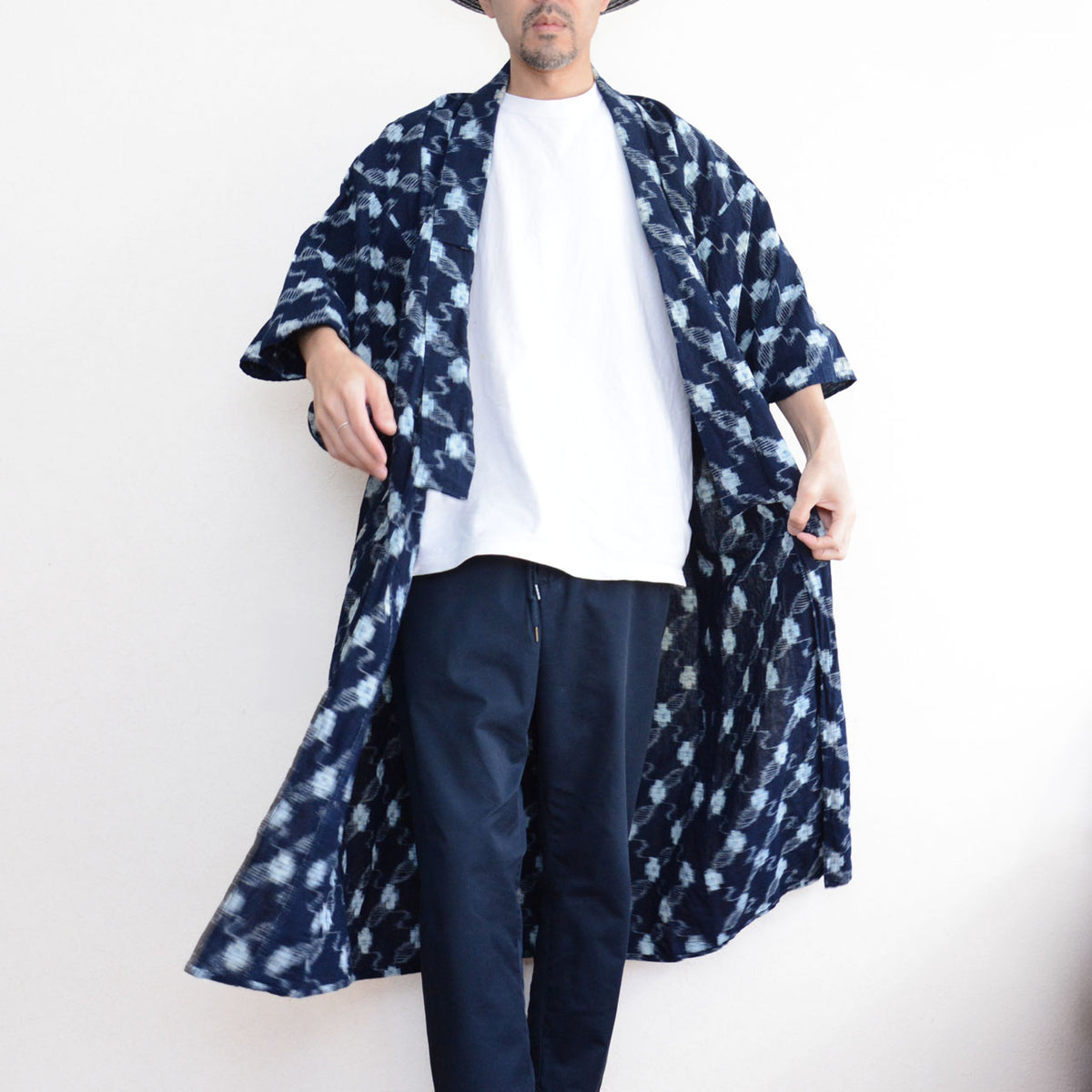 Male model wearing an indigo kasuri cotton kimono robe open over a white T-shirt and navy trousers