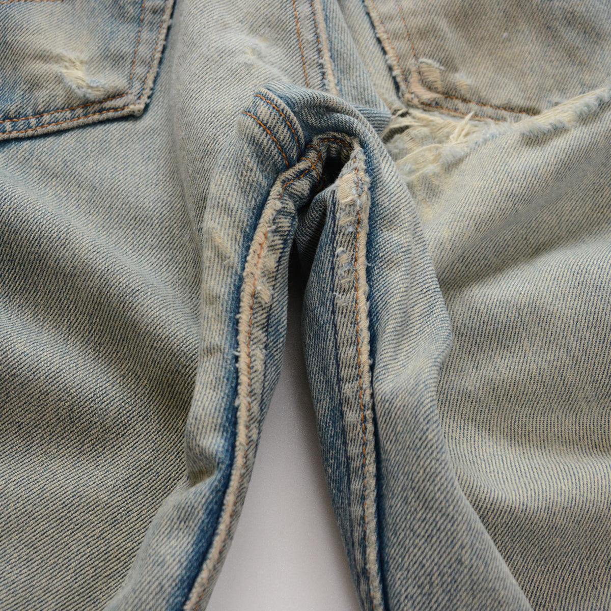 Levi’s 501 faded blue denim with abrasion and fraying along the crotch and inner leg seams