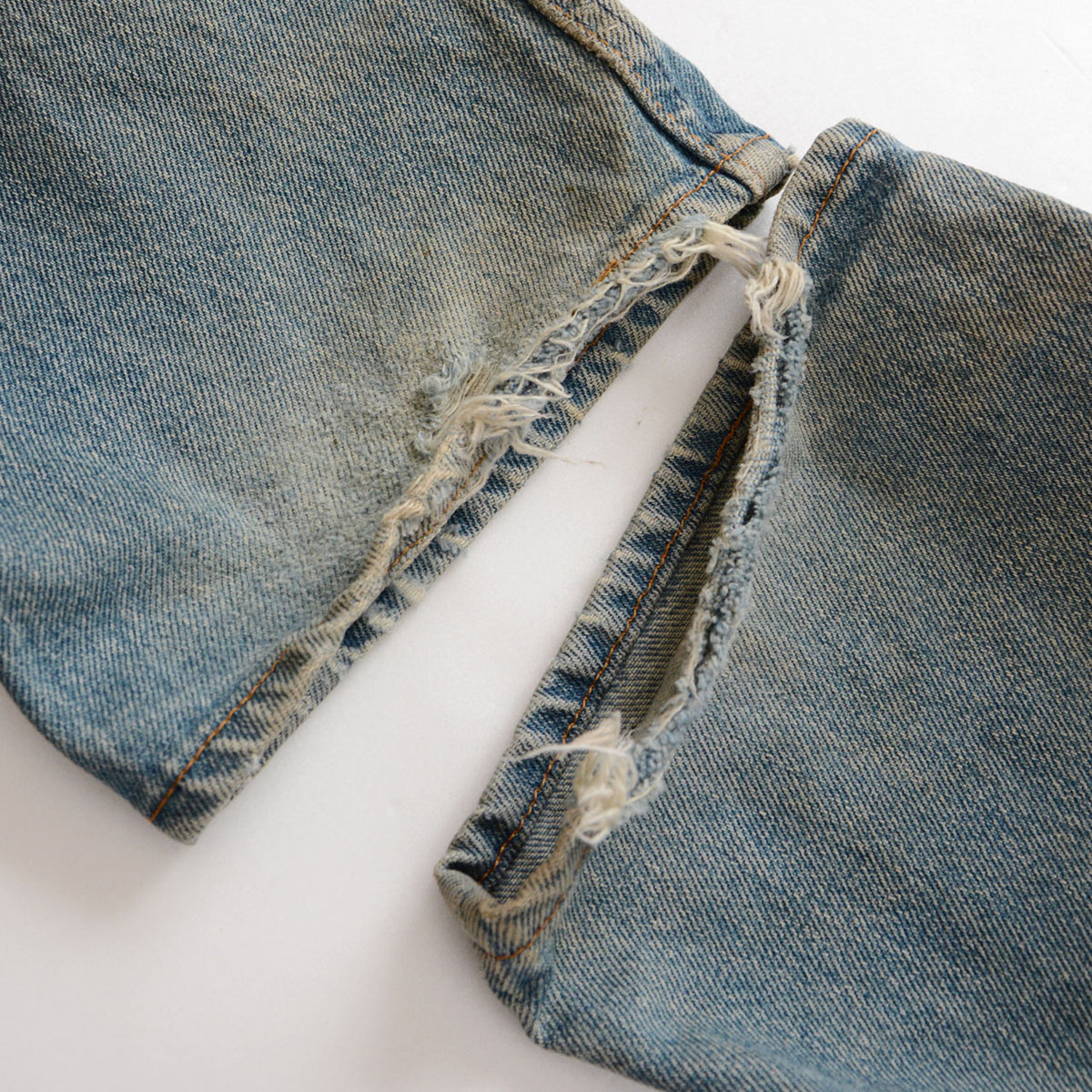 Levi’s 501 faded blue denim with worn and torn hems and frayed white threads